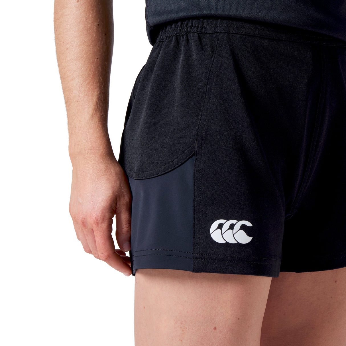 The person is wearing Women's Canterbury Advantage Short 2.0 in black, featuring a logo on the left side, designed by Canterbury for optimal performance against a plain backdrop.