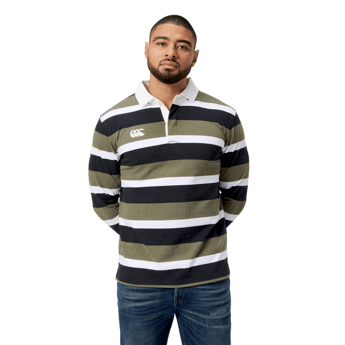 A person in a Canterbury Yarn Dye Long Sleeve Striped Rugby Jersey pairs it with jeans, standing with hands casually tucked behind their back.