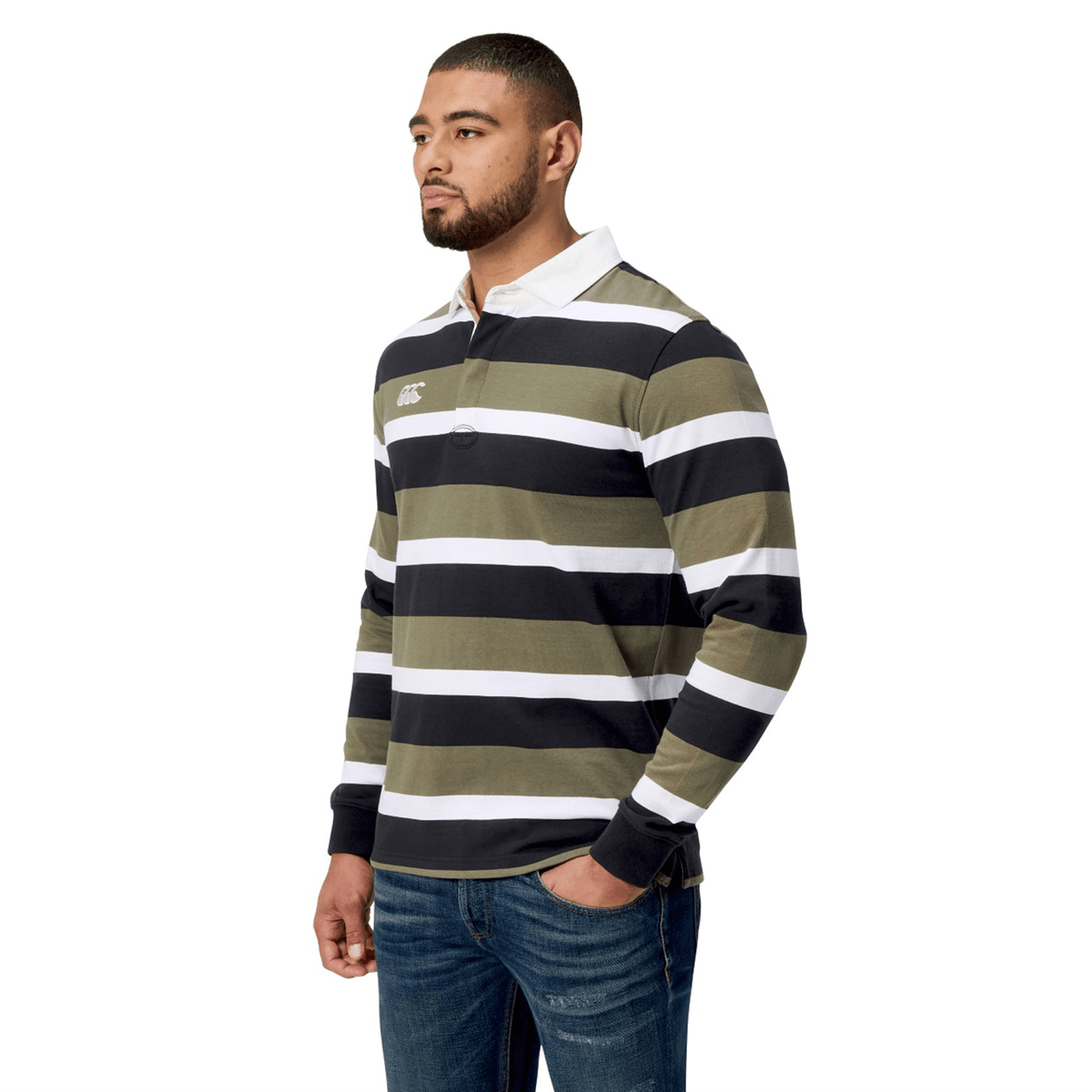 A man models the Canterbury Yarn Dye Long Sleeve Striped Rugby Jersey, featuring green and white stripes and a precise yarn-dyed finish, effortlessly paired with jeans against a plain white background.