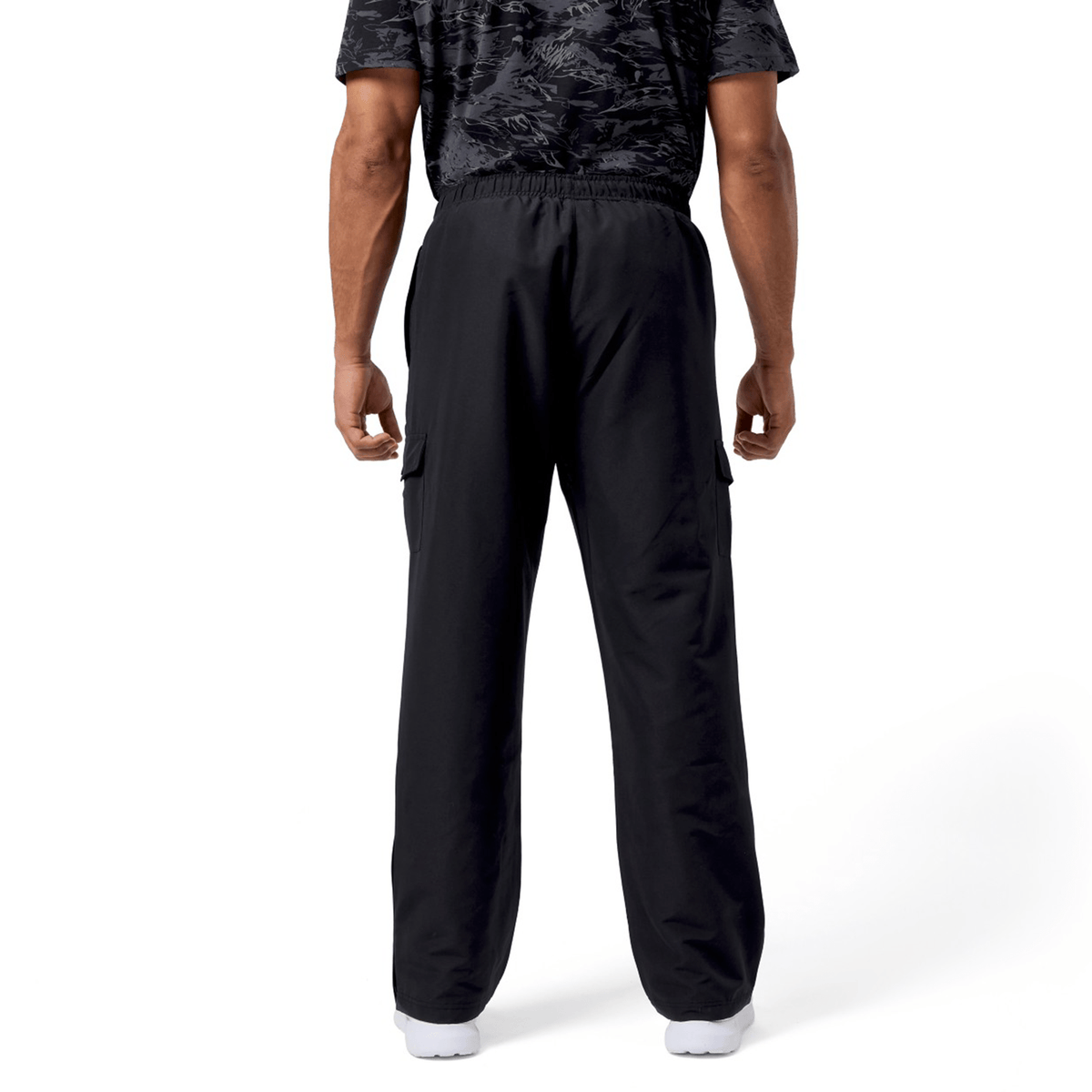 A person in a black patterned shirt and Canterbury Force Straight Leg Pant stands with their back to the camera against a white background.