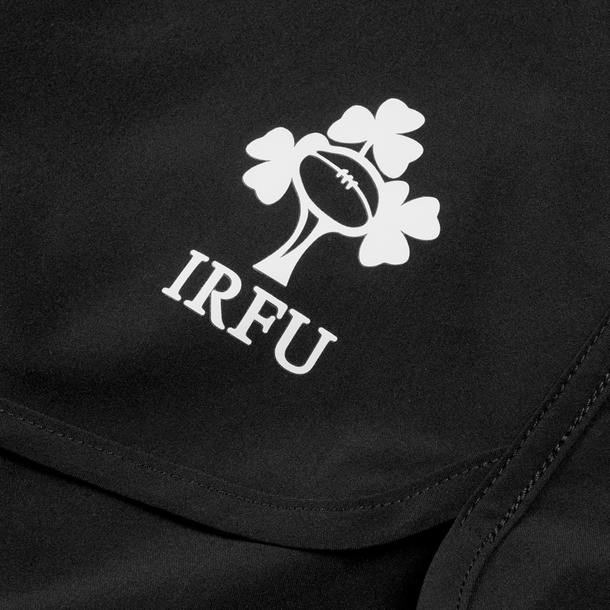 Close-up of Canterbury Women's Ireland 25/26 Woven Gym Shorts in black, showing the IRFU logo with a rugby ball and three shamrocks above "IRFU.