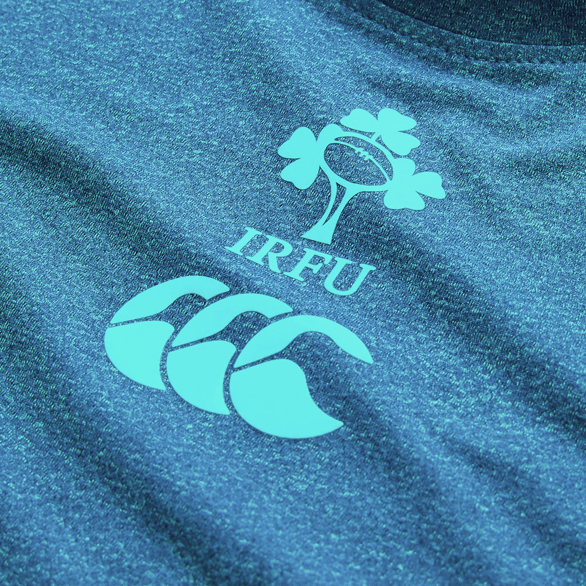 Close-up of the Ireland 26/27 Summer Tour Elite Training Tee by Canterbury, a blue rugby top featuring the IRFU logo with shamrock and rugby ball above the Canterbury brand logo.
