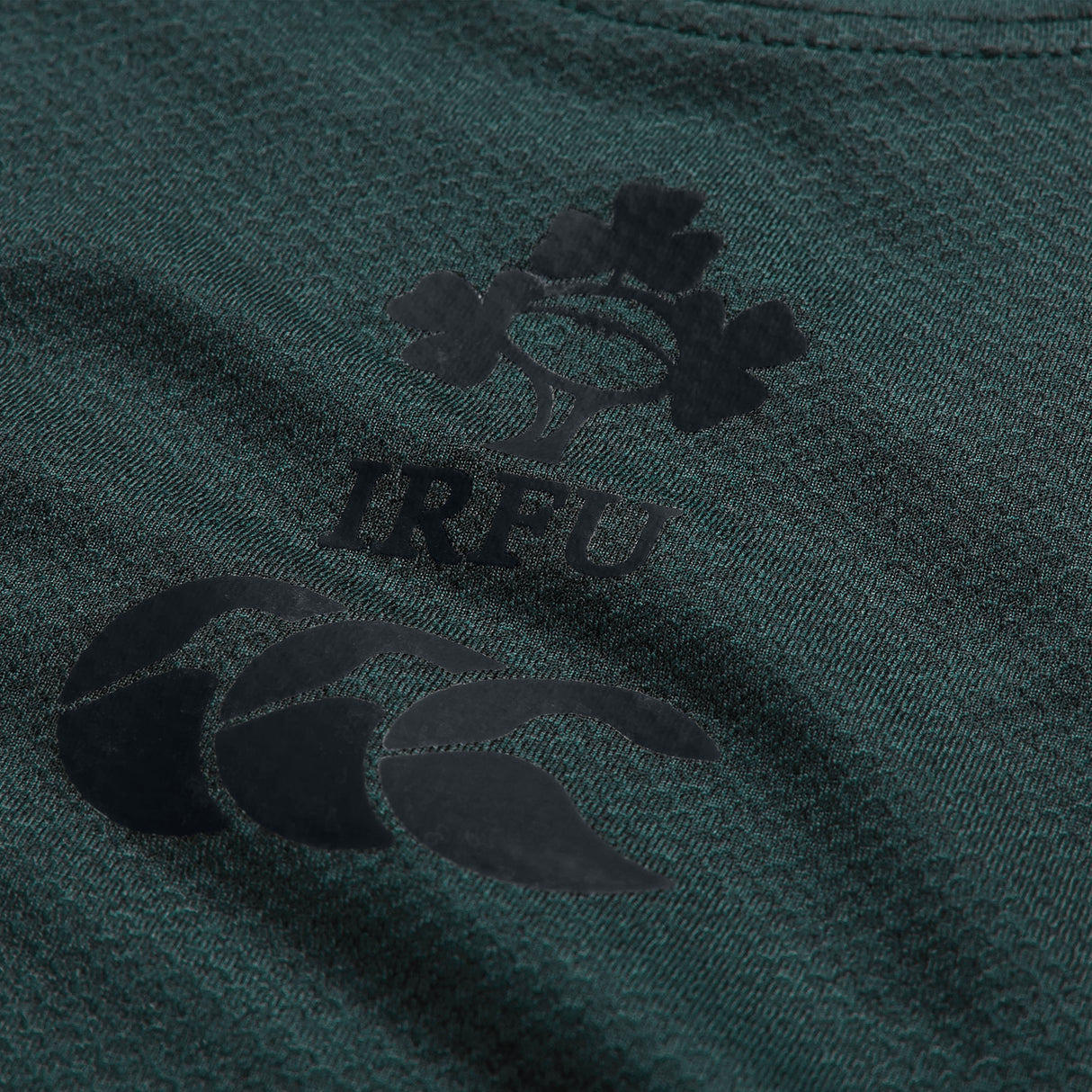Close-up of the Ireland 26 Elite Training Tee by Canterbury in green, showcasing the IRFU logo with a shamrock and rugby ball motif above the Canterbury brand logo. Crafted from Vapodri breathable sportswear, this elite training shirt is designed to deliver comfort and performance both on and off the field.