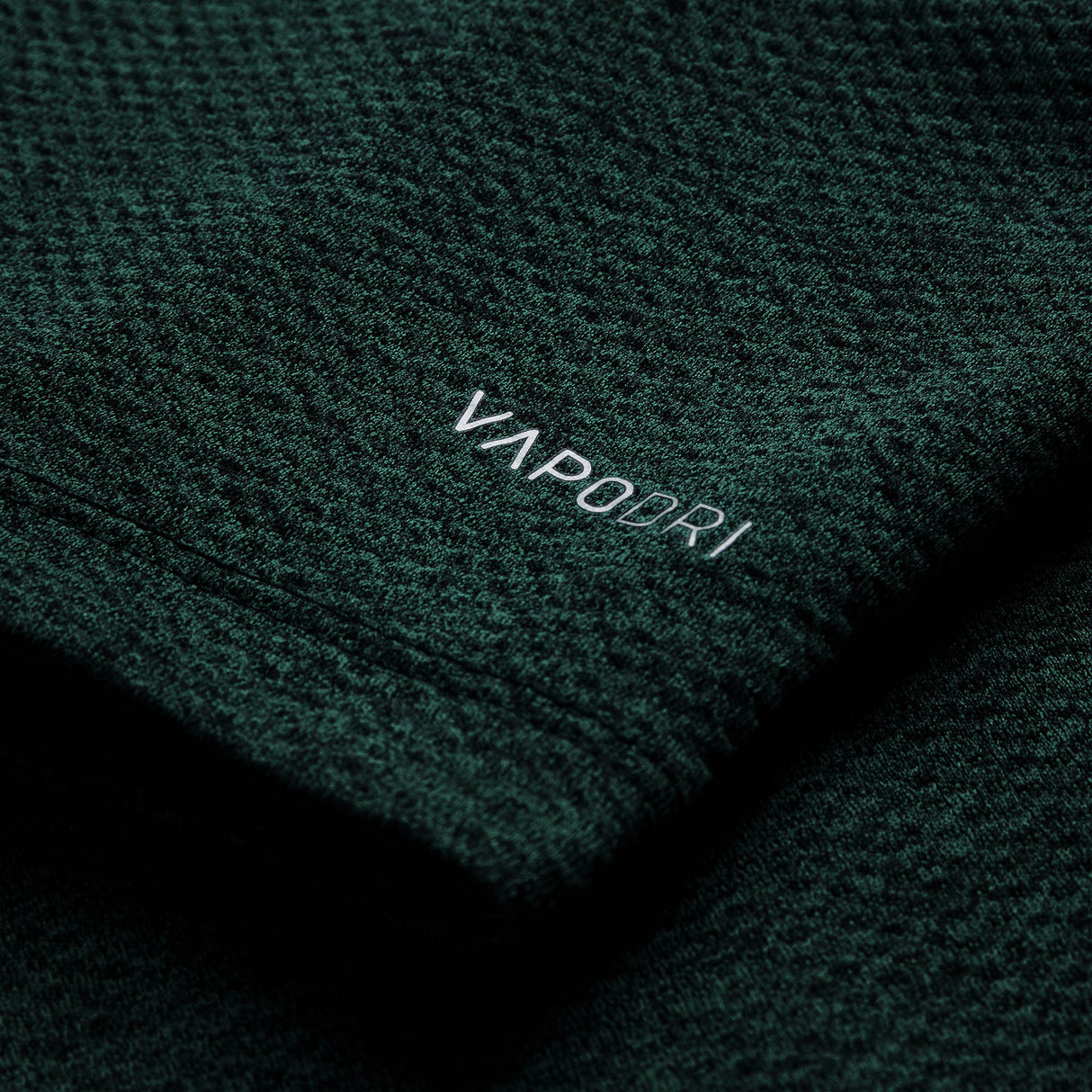 Close-up of dark green textured fabric from the Ireland 26 Elite First Layer by Canterbury, featuring the word “VAPODRI” printed in white text.