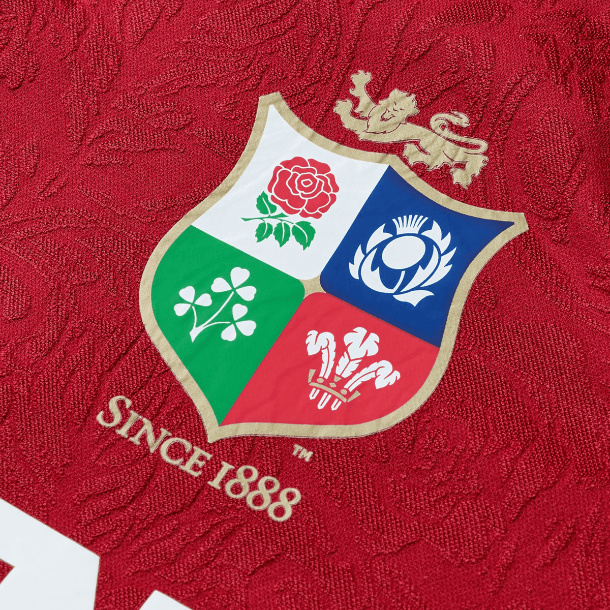 The Youth British & Irish Lions 2025 Players Jersey by Canterbury, colored red and detailed with a crest of a lion, rose, thistle, shamrock, and three feathers, boasts ergonomic paneling and moisture-wicking fabric. It proudly features "Since 1888" for lasting comfort and style.