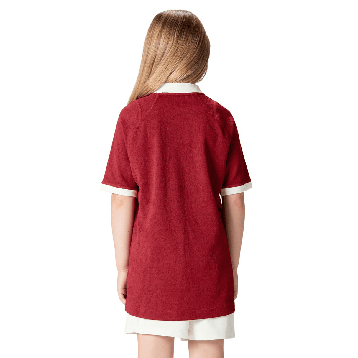 A child with long hair, facing away, sports the Youth British & Irish Lions 2025 Players Jersey by Canterbury, featuring a red design and subtle ergonomic paneling.