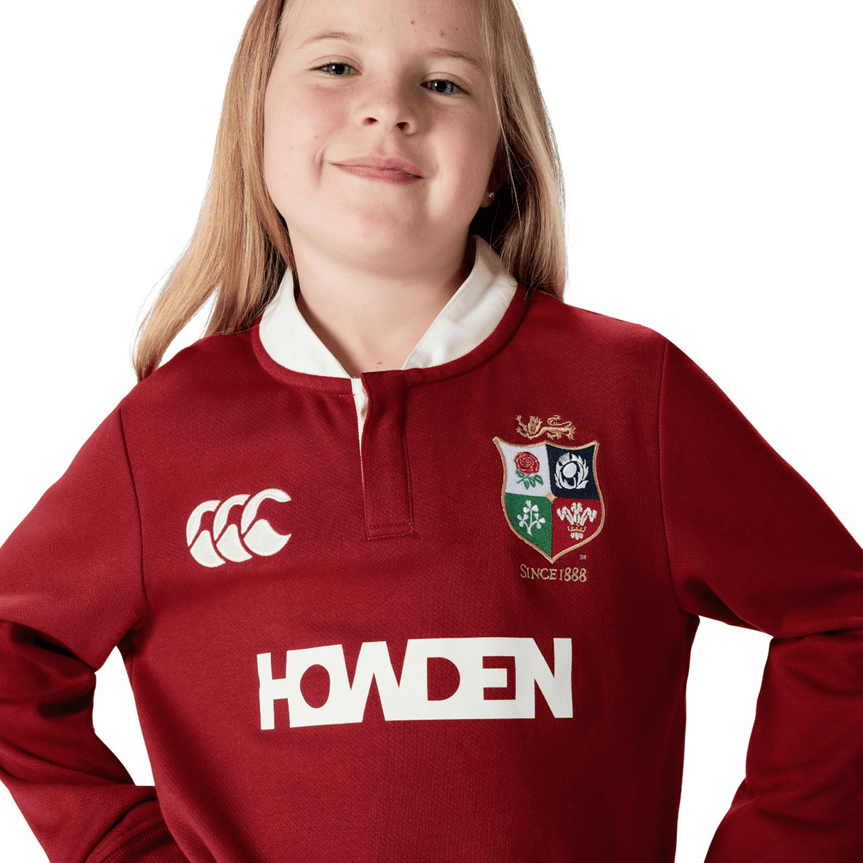 A young person confidently poses against a white background, wearing the Youth British & Irish Lions 2025 Long Sleeve Classic Jersey by Canterbury. This jersey features logos and moisture-wicking fabric for comfort and style.