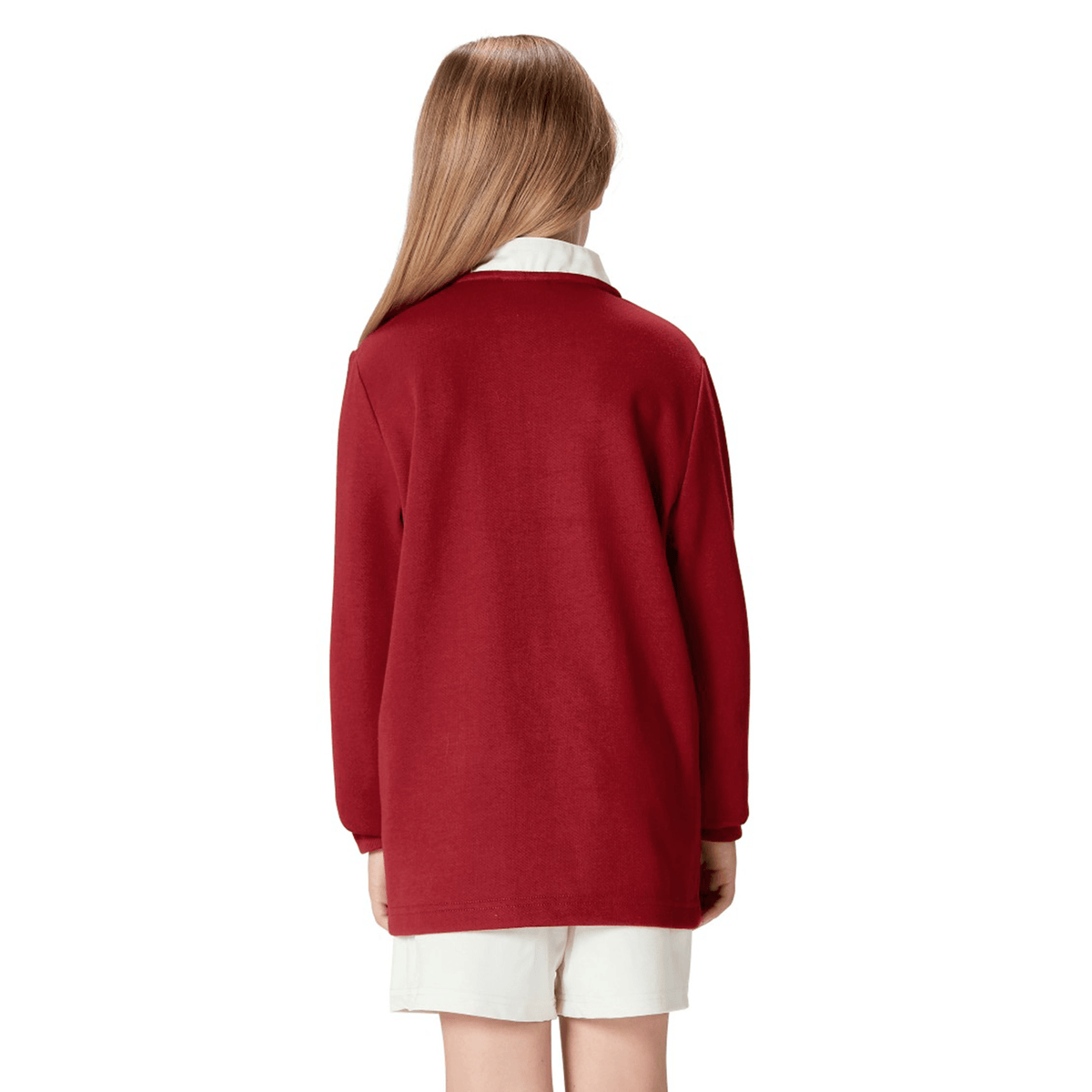 Rear view of a child wearing the Youth British & Irish Lions 2025 Long Sleeve Classic Jersey by Canterbury in red, paired with white shorts, with long hair cascading down their back.