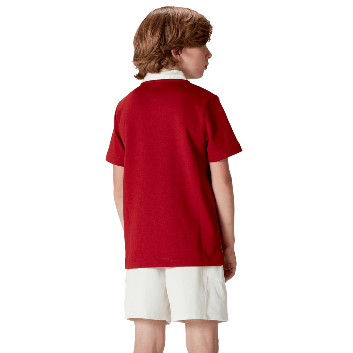 A brown-haired child, wearing the Youth British & Irish Lions 2025 Classic Jersey by Canterbury and white shorts, stands facing away.