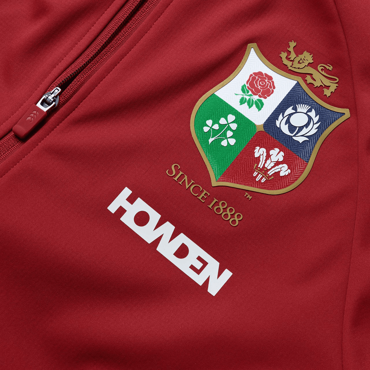 The British & Irish Lions 2025 Anthem Jacket by Canterbury boasts a crest with a lion, rose, thistle, shamrock, and leek labeled “Since 1888,” with a Howden logo beneath. It's the perfect way to display your team spirit.