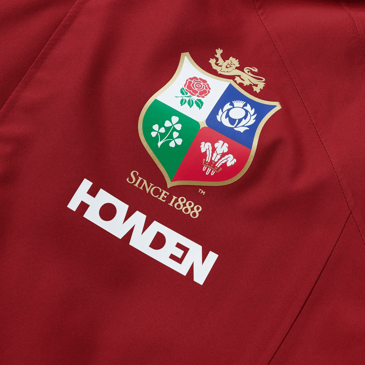 Close-up of a red polyester jacket featuring a rugby emblem with four national symbols and "Since 1888" above the Canterbury brand name. This waterproof jacket captures the essence of the British & Irish Lions and is part of their 2025 collection by Canterbury.