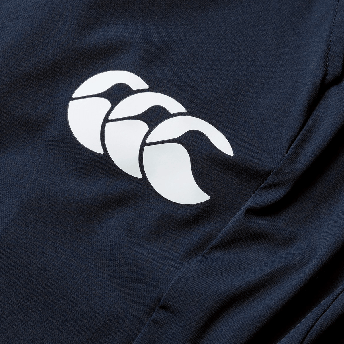Close-up of a navy quick-drying fabric on the British & Irish Lions 2025 Everest Woven Pant by Canterbury, showcasing a white logo with three overlapping, curved shapes.