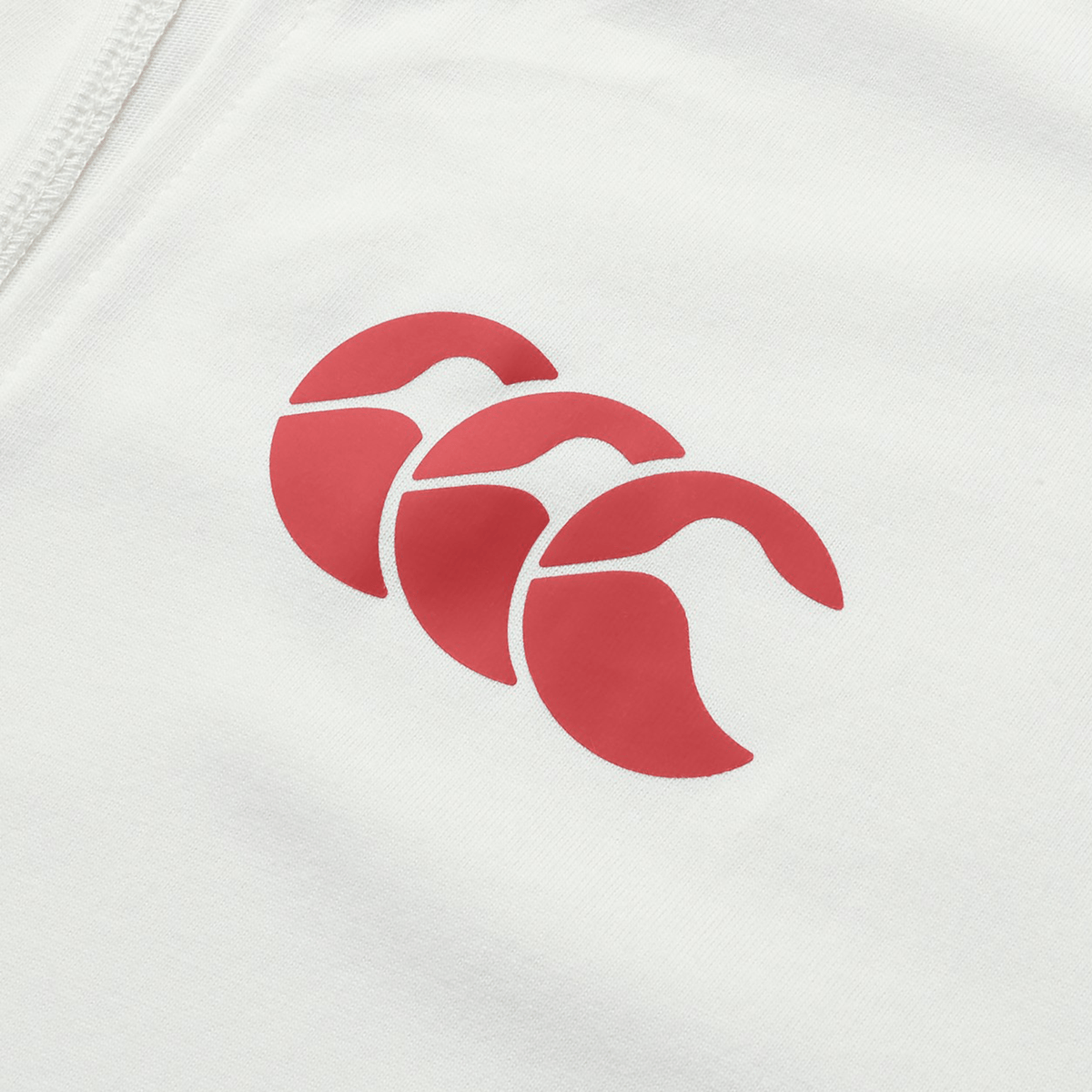 Close-up of the Canterbury logo featuring three overlapping shapes in red and white on a cotton fabric surface, evoking the iconic aesthetic of the British & Irish Lions 25 Cotton Muscle Tank by Canterbury.