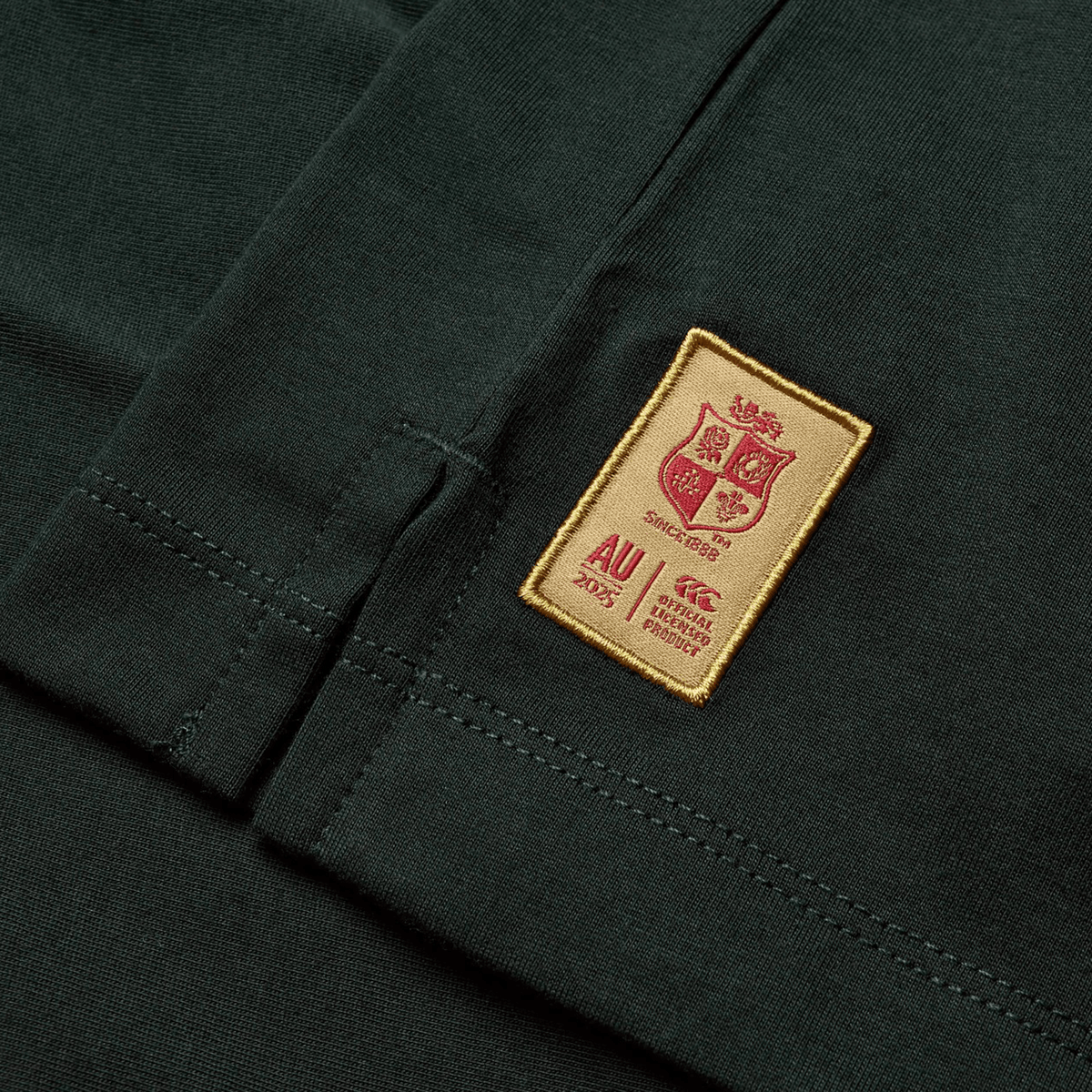 Close-up of the British & Irish Lions 25 Cotton Muscle Tank reveals a green fabric adorned with a rectangular patch. This patch displays a crest design, the text "Since 1888," and logos for AU 2025, CCC, and Lions, all crafted by Canterbury to evoke the spirit of the British & Irish Lions.