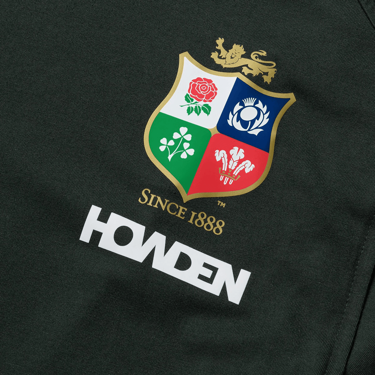 A detailed close-up of the Canterbury logo for the British & Irish Lions 25 collection, featuring a rose, thistle, clover, and feathers. The text "Since 1888" is prominently displayed below the logo, while "Howden" is elegantly inscribed in white. This tank offers perfect detailing for your Cotton Muscle Tank collection.
