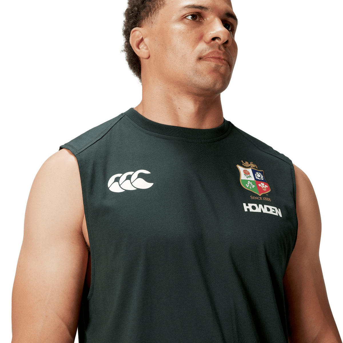 An individual is wearing a sleeveless dark green sports jersey adorned with prominent logos on the chest. This British & Irish Lions 25 Cotton Muscle Tank by Canterbury exudes the athletic spirit commonly linked to teams such as the British & Irish Lions.