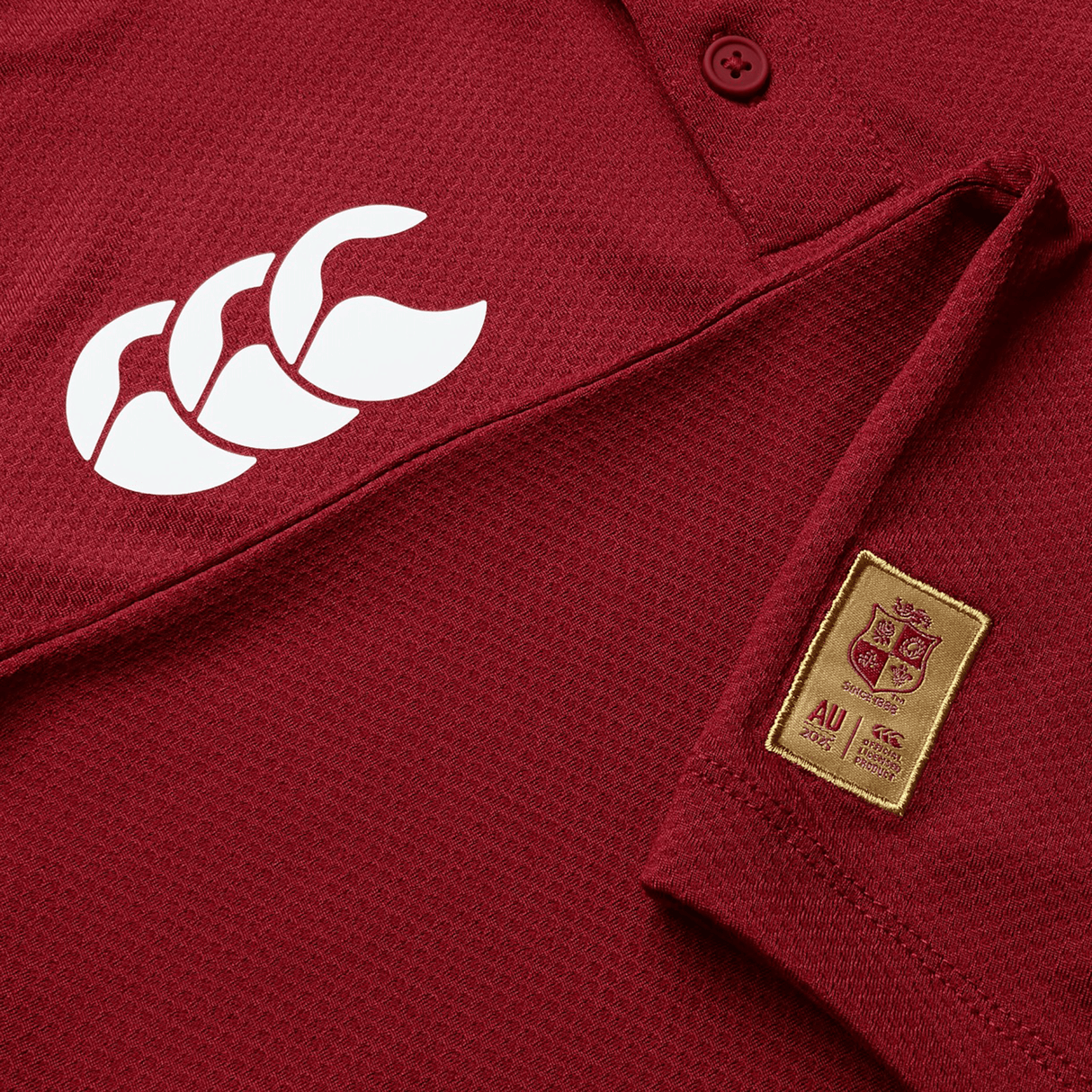 Close-up of a maroon British & Irish Lions Poly Polo, made from breathable fabric, featuring a prominent white Canterbury logo and an AU patch with crest and text.