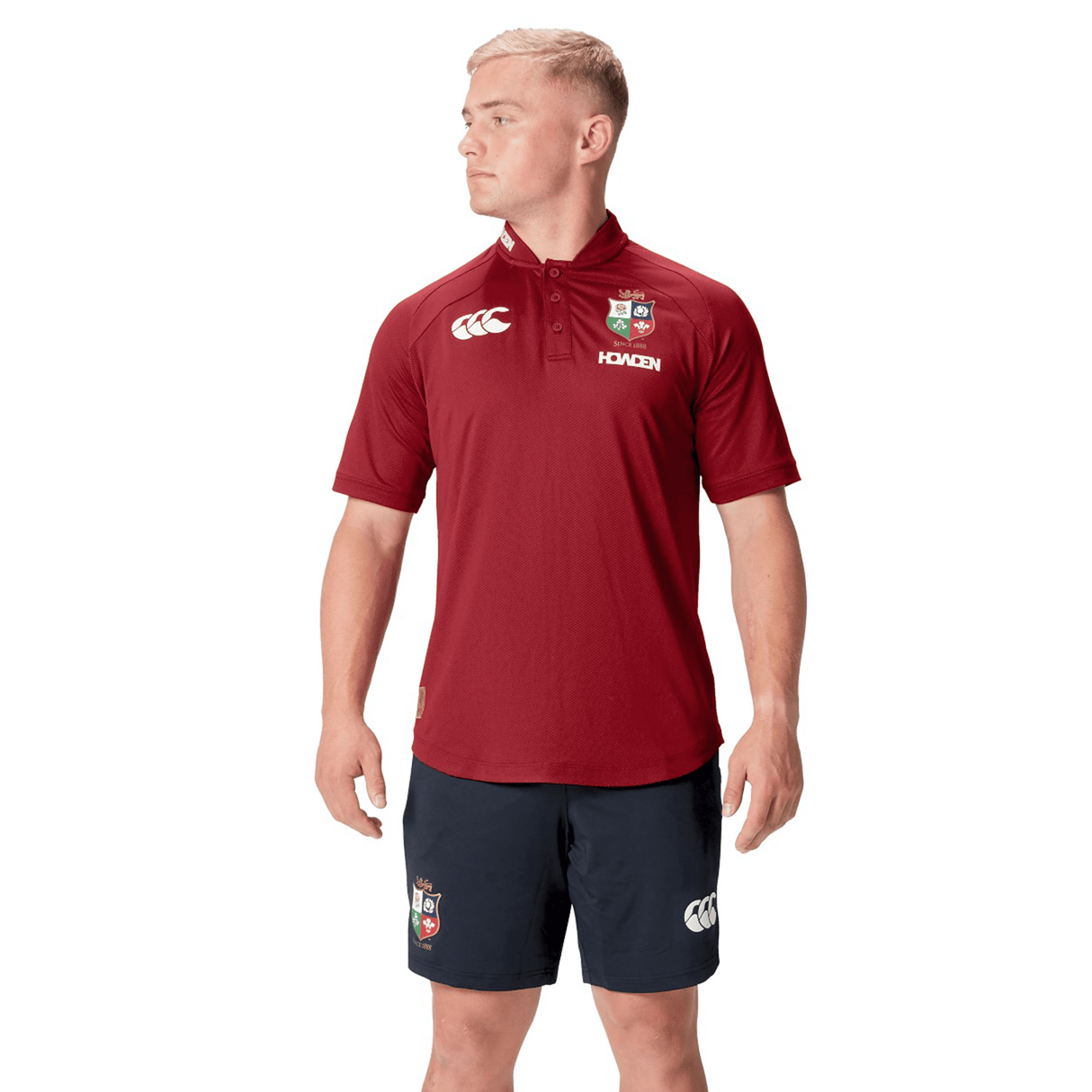 Dressed in the British & Irish Lions 25 Poly Polo by Canterbury in maroon and navy logo shorts, a person stands against a white background, perfectly capturing the classic style of the collection.