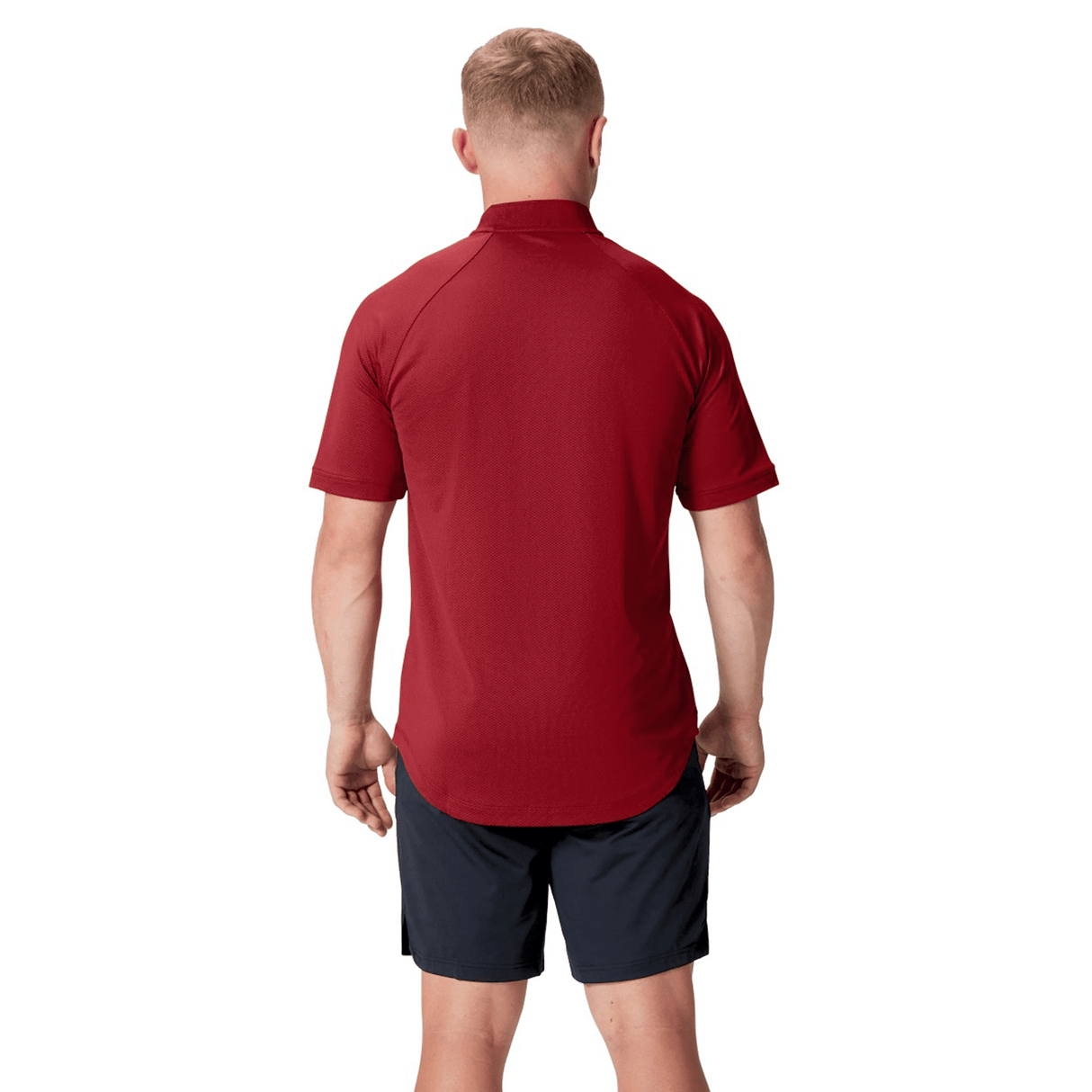 A man with his back to the camera wears the British & Irish Lions 25 Poly Polo by Canterbury in red, designed for breathability, paired with black shorts against a pristine white background.