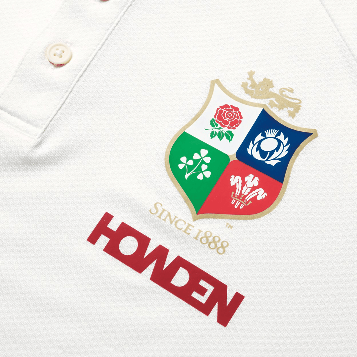 Close-up of the British & Irish Lions 25 Poly Polo by Canterbury, showcasing a four-part shield crest with a rose, thistle, shamrock, and dragon. Decorated with "SINCE 1888" and "HOWDEN" in red lettering, this quick-drying polo also features an embossed BIL neck tape for an extra touch of style.