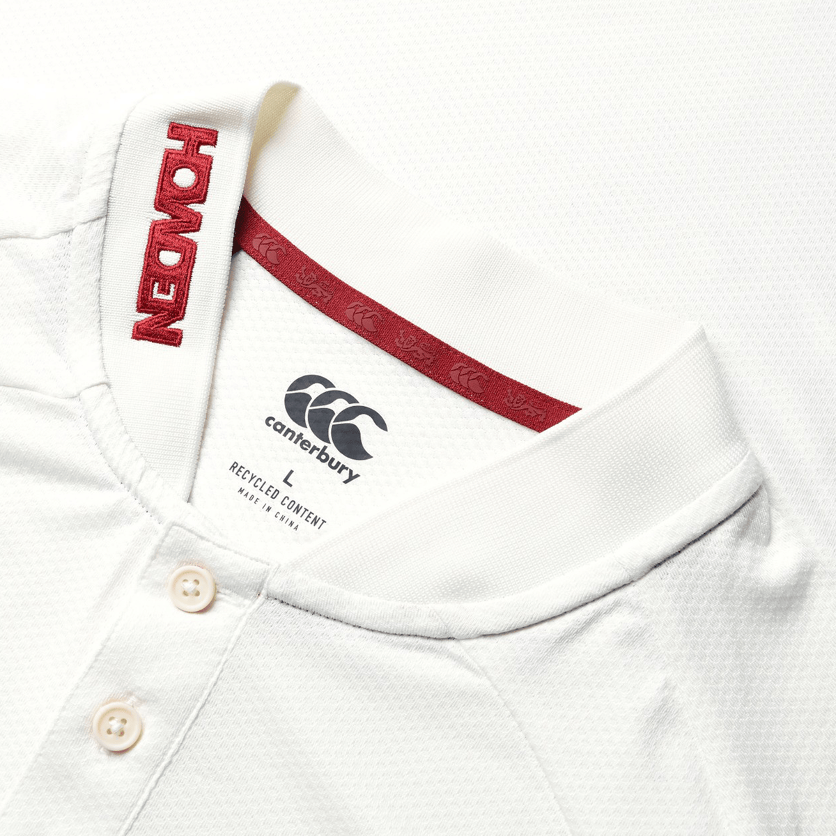 Here's a detailed look at the British & Irish Lions 25 Poly Polo by Canterbury, showcasing a white fabric adorned with a red "HONDA" logo on the collar. Ideal for fans of the British & Irish Lions, this polo shirt features three buttons and interior neck labels.