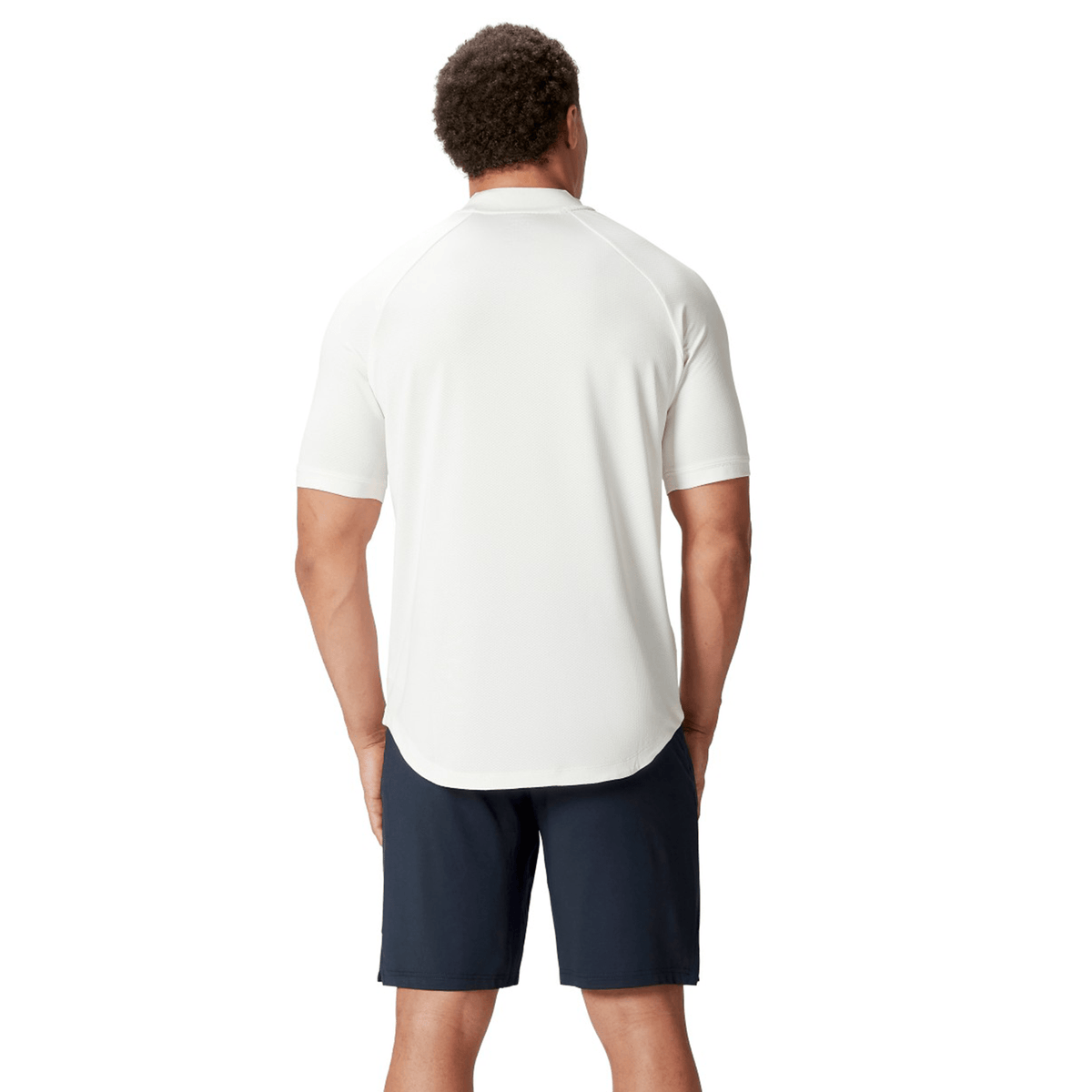 A man with short curly hair, wearing the British & Irish Lions 25 Poly Polo by Canterbury and navy shorts, stands with his back turned, exuding the timeless charm of the British & Irish Lions.