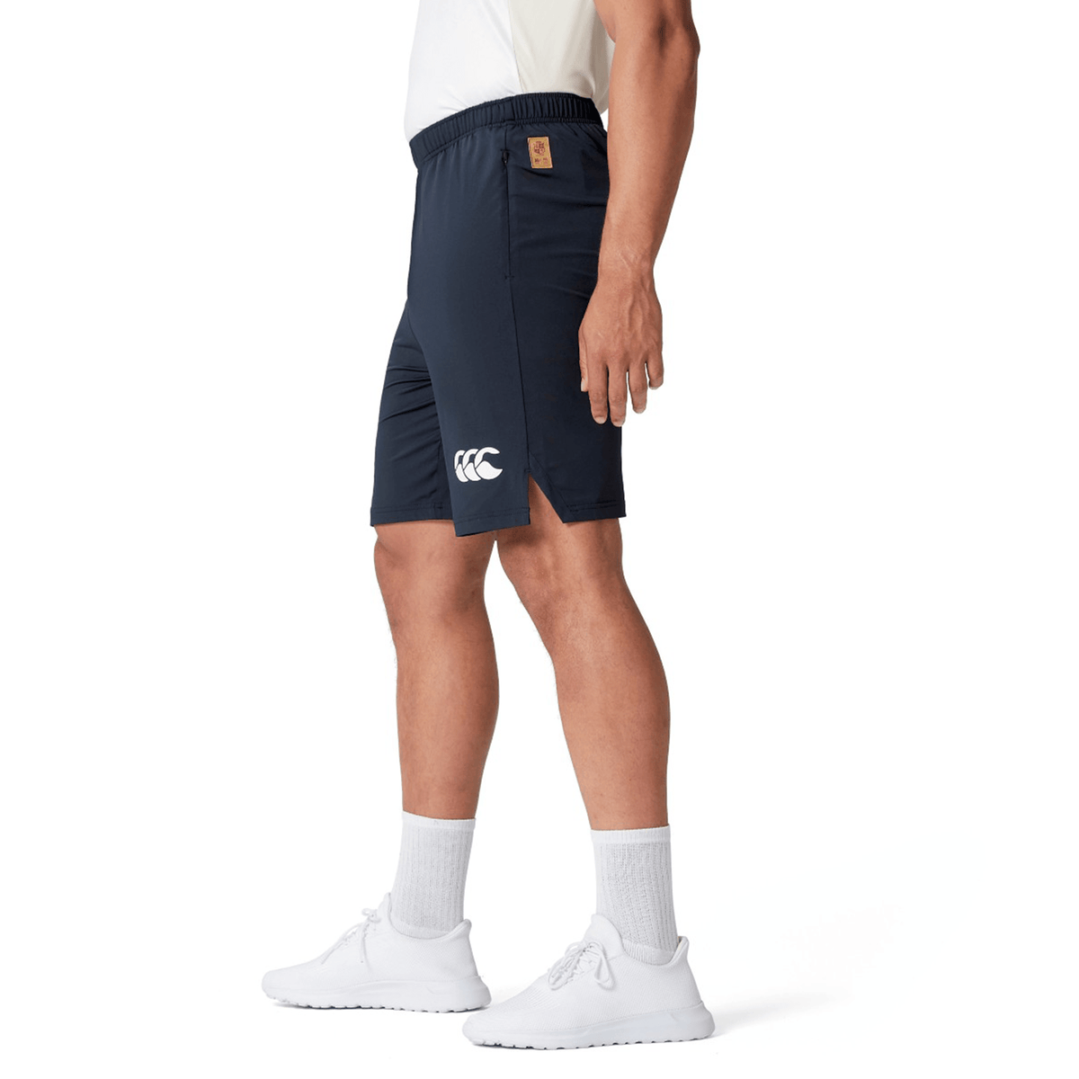 Person wearing the British & Irish Lions 2025 Training Shorts by Canterbury in navy and white shoes, standing sideways.