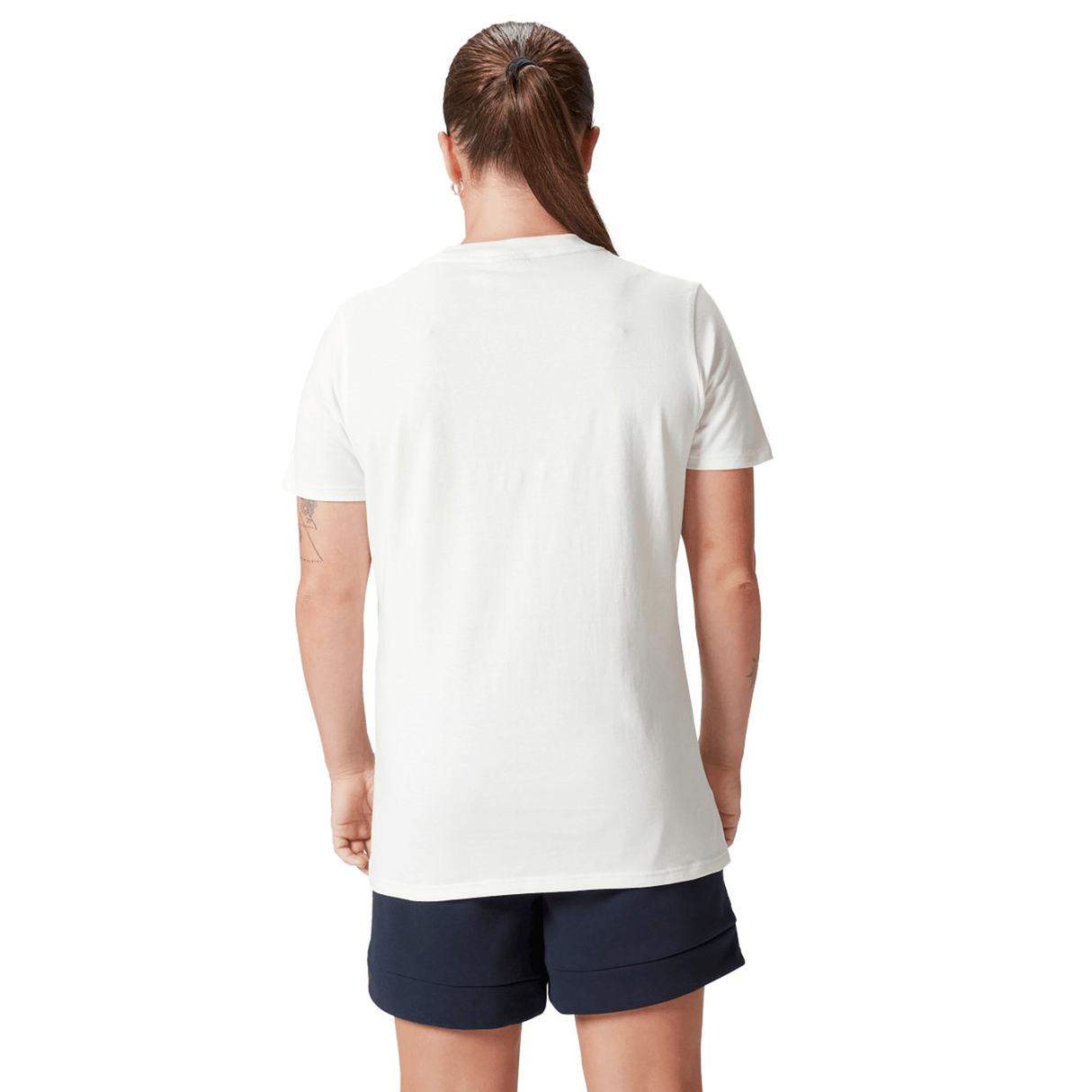 A person with a ponytail stands with their back to the camera, wearing a Women's British & Irish Lions 25 Cotton Jersey Tee by Canterbury and dark shorts.
