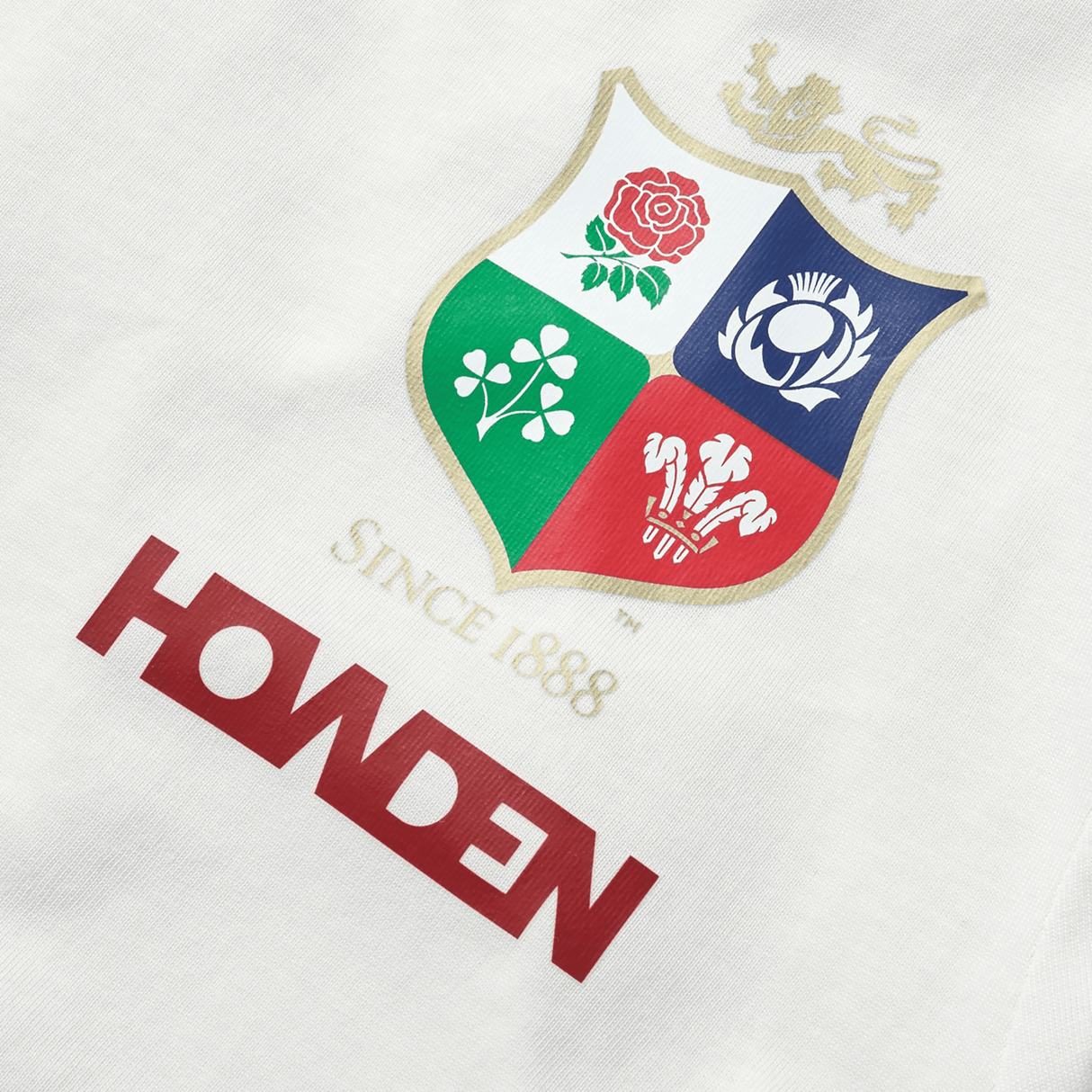 The Women's British & Irish Lions 25 Cotton Jersey Tee by Canterbury showcases a logo with a shield featuring a lion, rose, shamrock, thistle, and feathers to celebrate the British & Irish Lions. Above the logo is text reading "Since 1888" and "Howden" on a white background. This tee is perfect for any rugby supporter seeking timeless elegance.