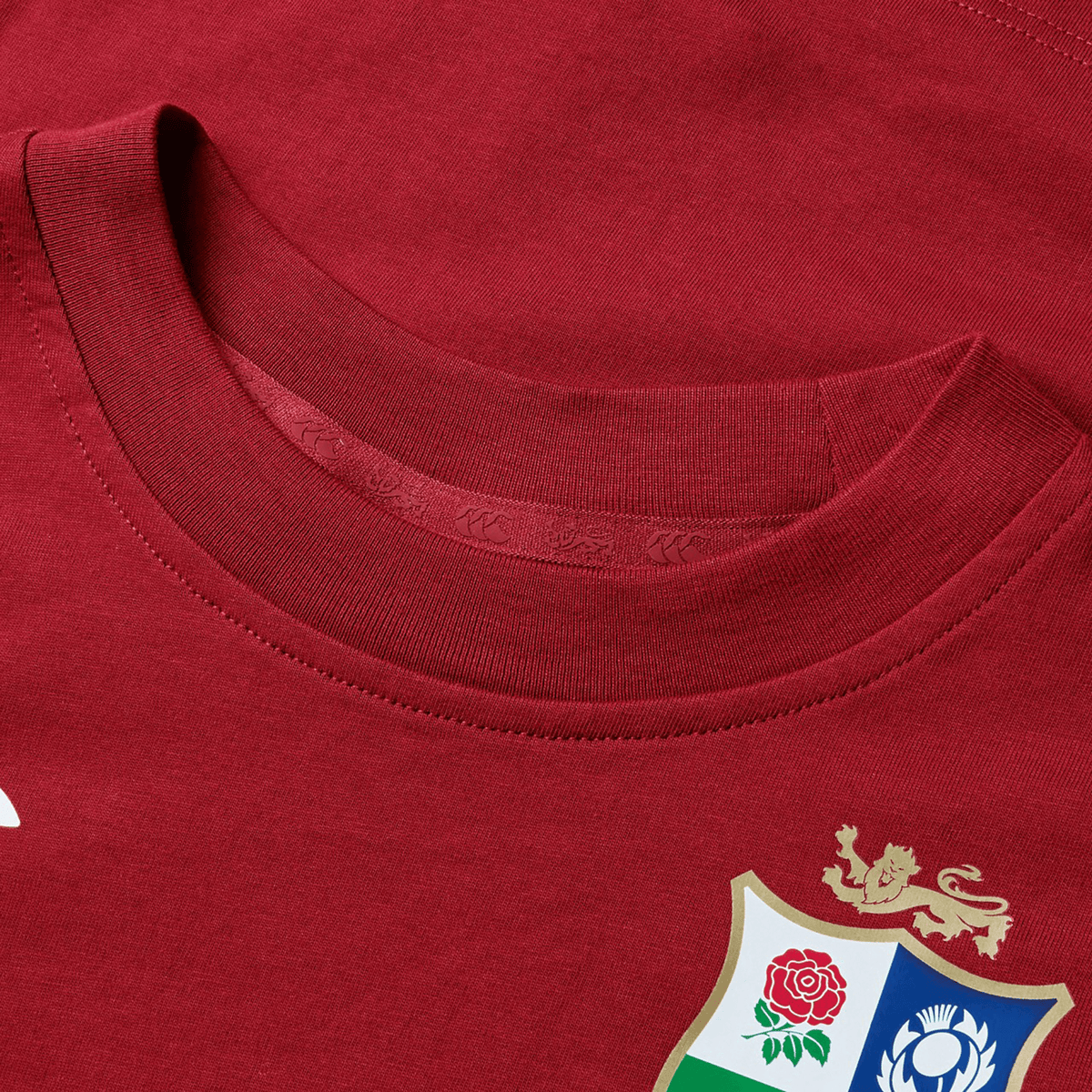 The Youth British & Irish Lions 2025 Cotton Jersey Tee by Canterbury is a red sports jersey made from organic cotton, featuring a floral and animal crest on the chest—perfect for rugby supporters.