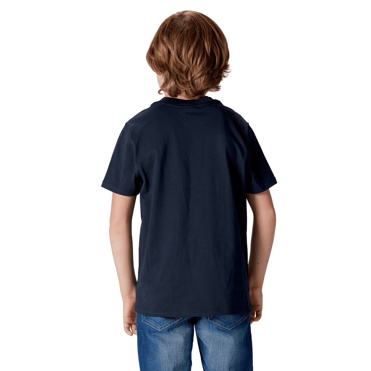 A child with long hair stands facing away, wearing a Youth British & Irish Lions 2025 Cotton Jersey Tee by Canterbury and jeans, perhaps dreaming of supporting the team in the future.