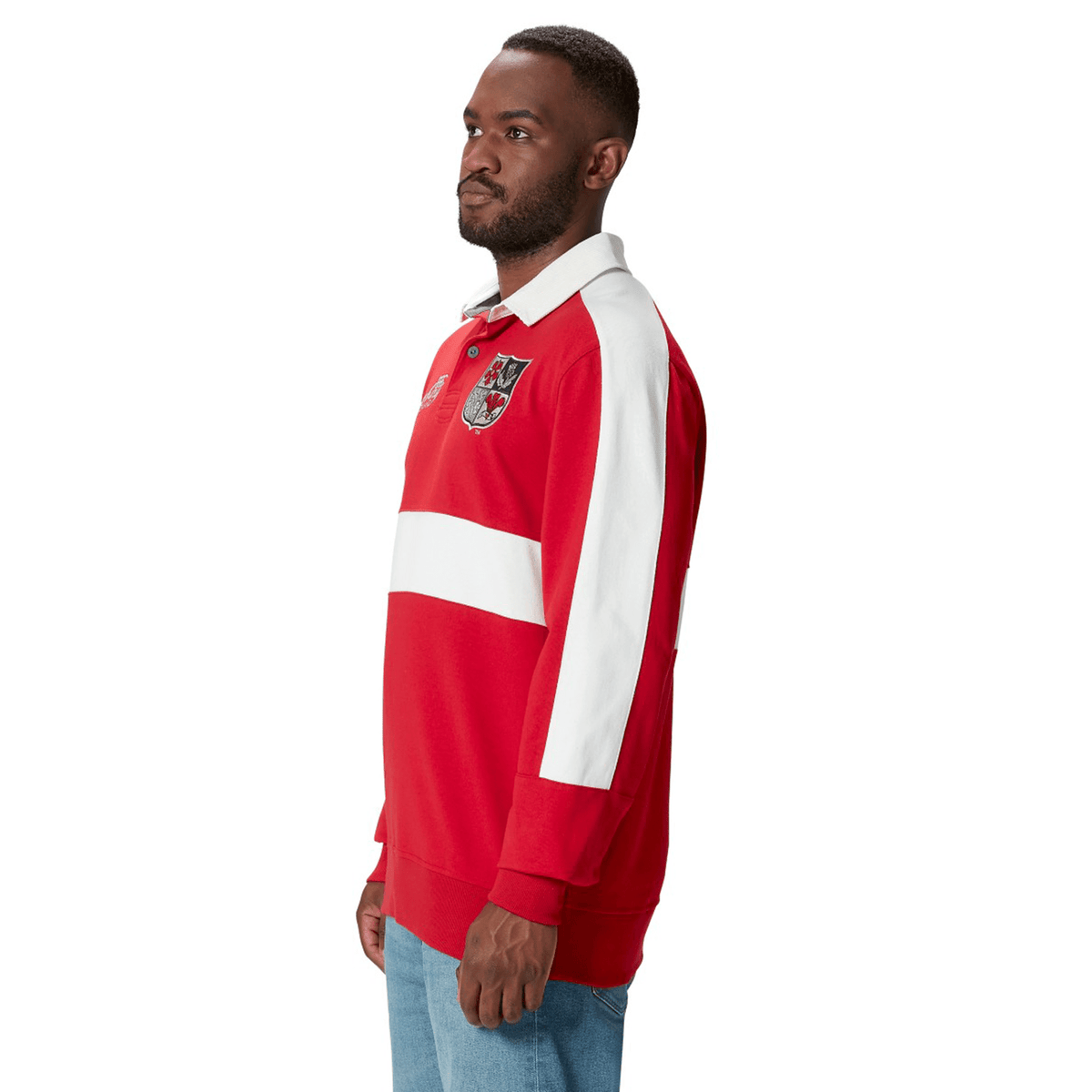 A man stands in profile wearing a red and white British & Irish Lions 2025 Heritage Jersey by Canterbury, featuring an emblem on the chest.