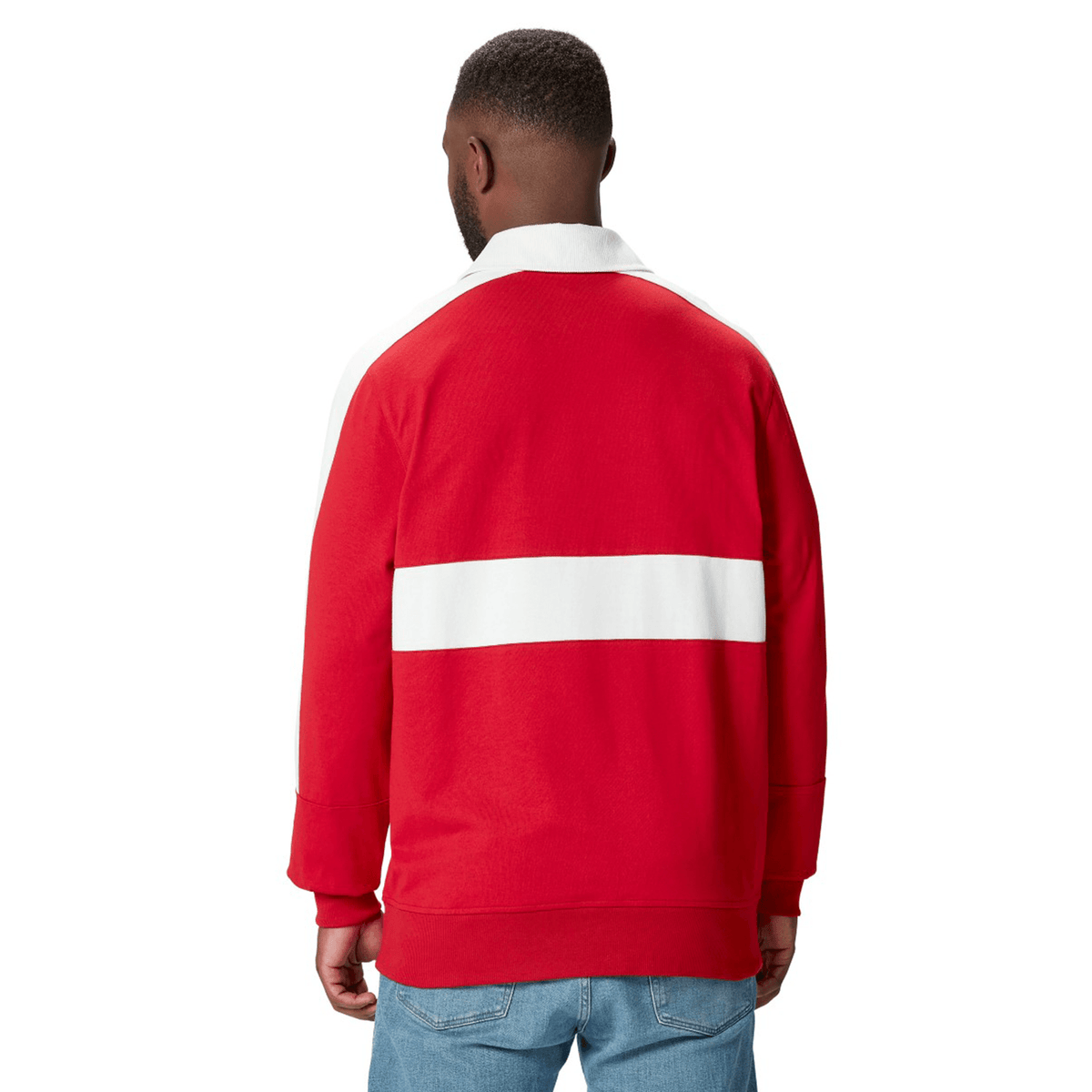 A person wearing a red and white British & Irish Lions 2025 Heritage Jersey by Canterbury and blue jeans stands facing away.