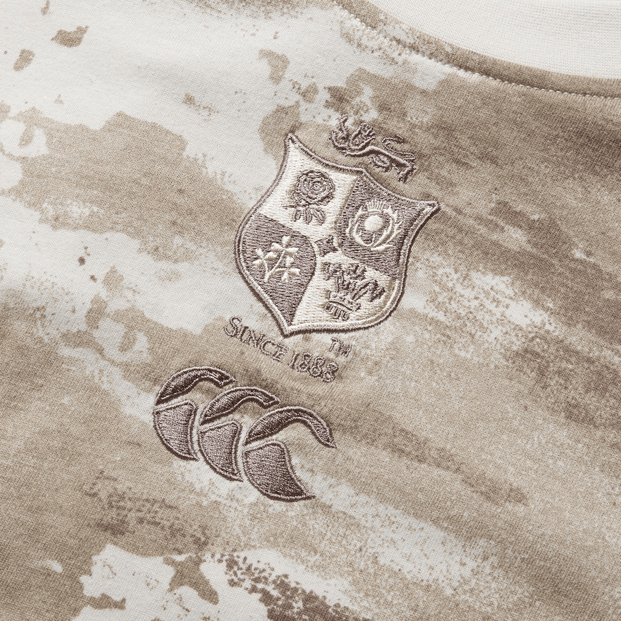 A close-up of a Desert Taupe camo tee, part of the British & Irish Lions 2025 collection by Canterbury, showcases the British and Irish Lions logo, the text "Since 1888," and the Canterbury logo.