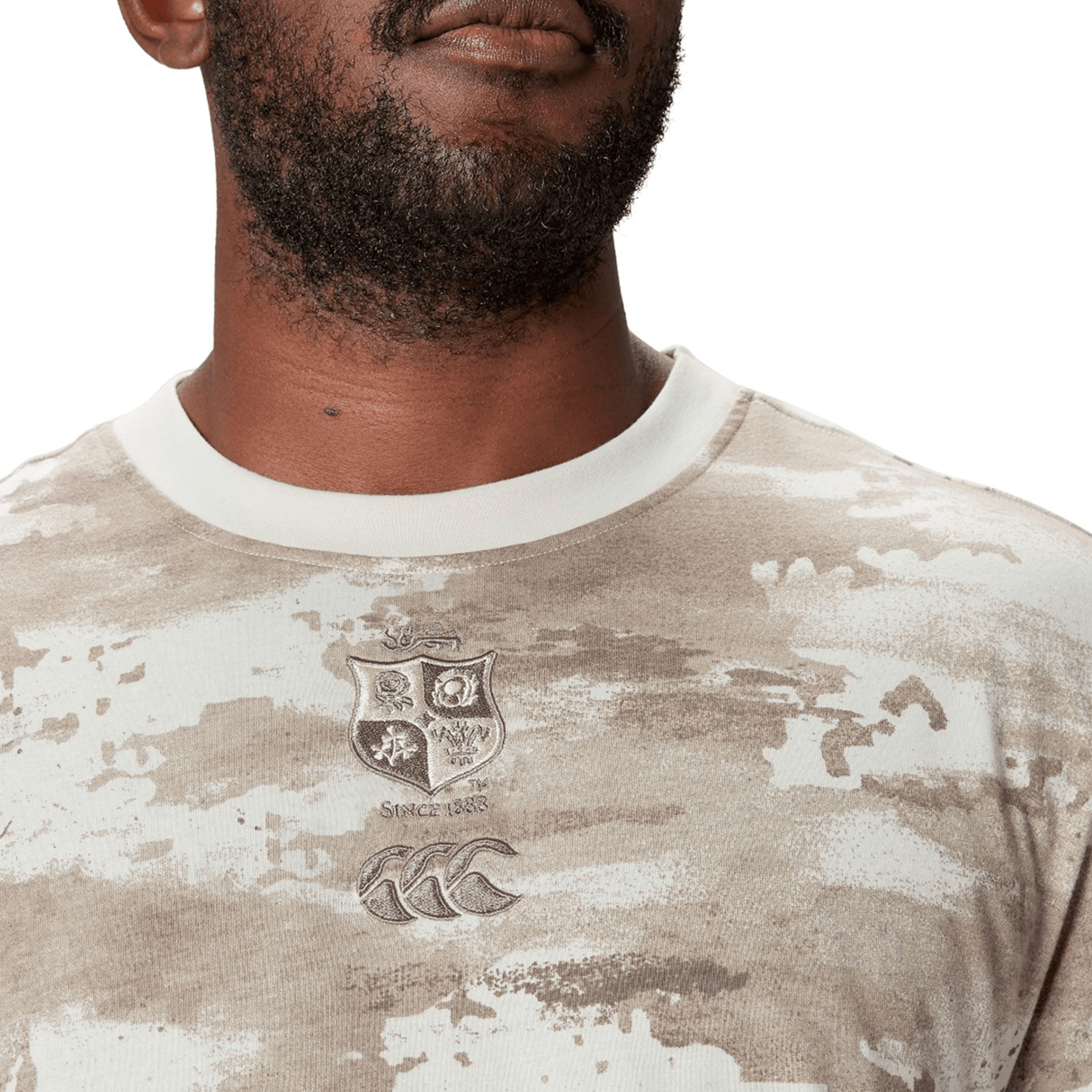 A man in a British & Irish Lions 2025 Camo Tee by Canterbury, featuring a crest and logo on the chest.