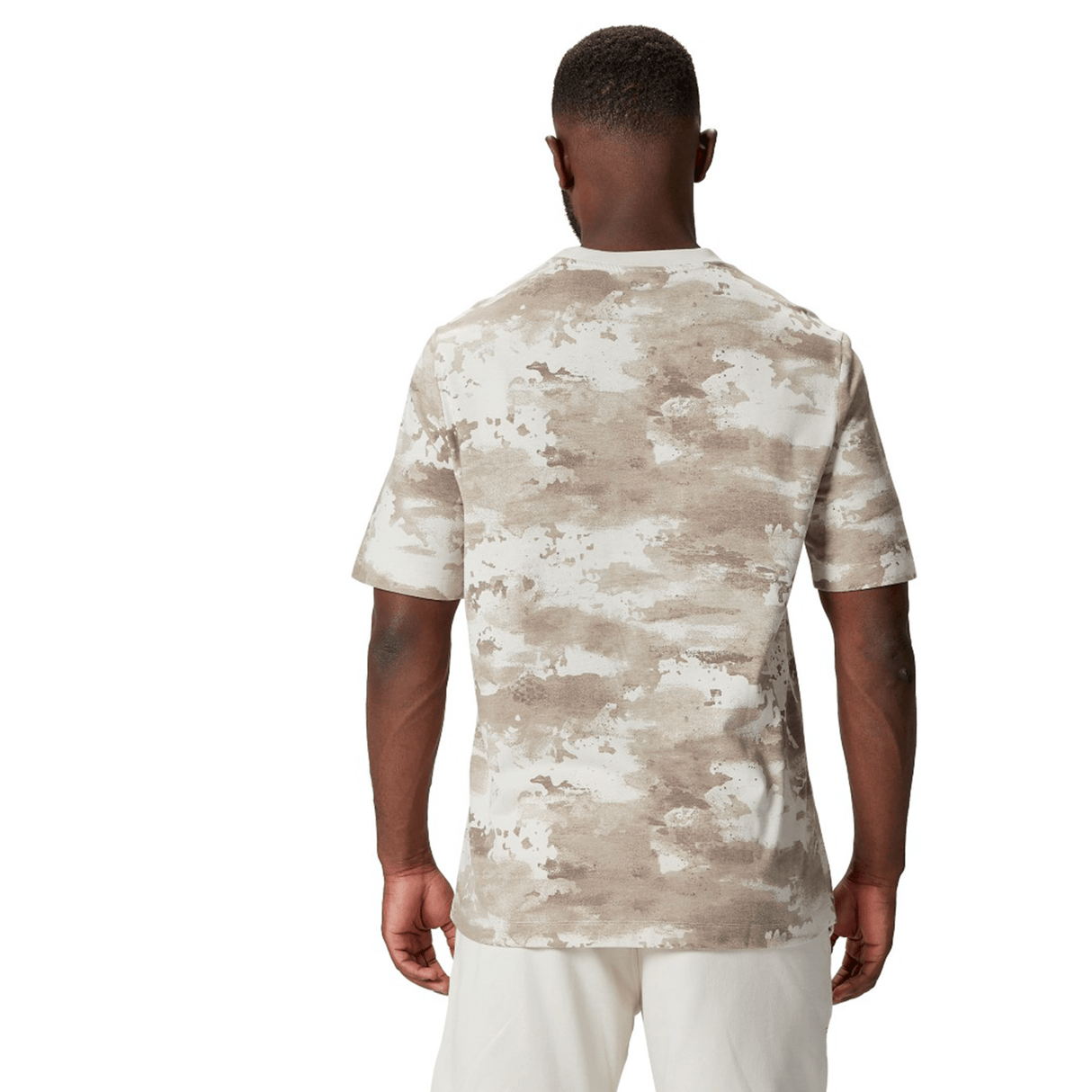 A person wearing the British & Irish Lions 2025 Camo Tee by Canterbury in Desert Taupe and white pants is shown from the back.