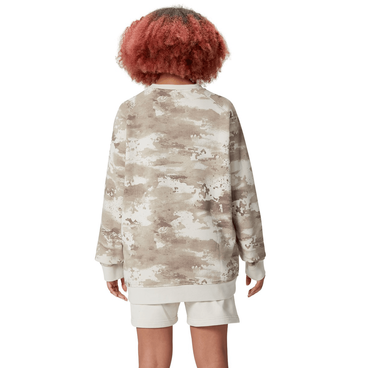 A person with curly hair is wearing the British & Irish Lions 25 Camo Crew Sweatshirt by Canterbury along with white shorts, facing away from the camera.