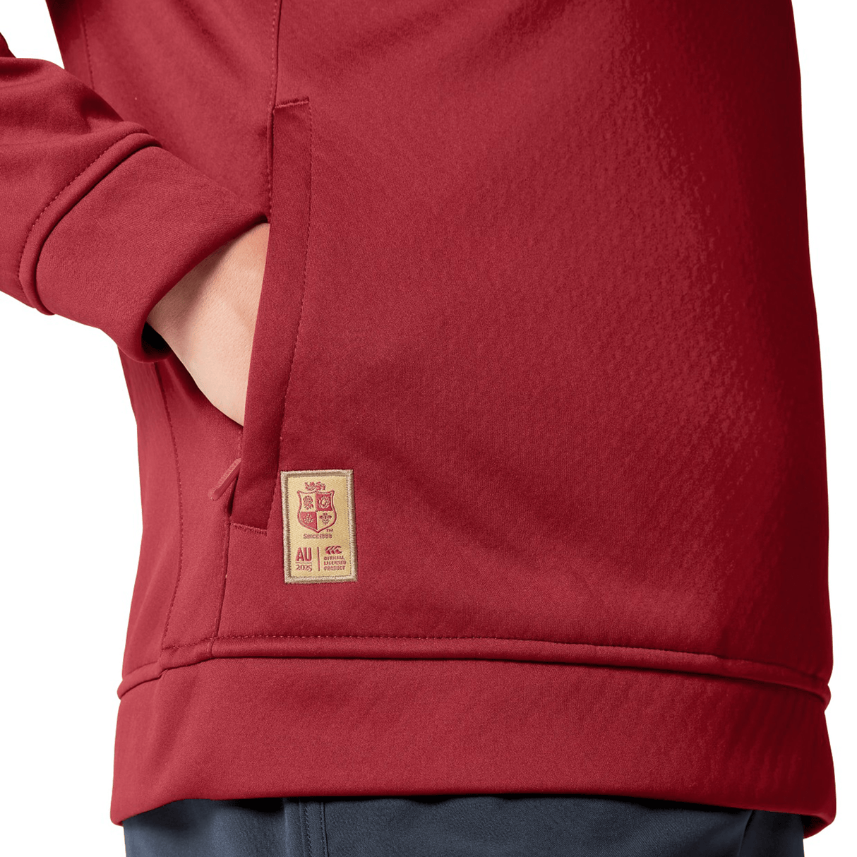 Close-up of a person wearing a Women's British & Irish Lions 2025 1/4 Zip Fleece by Canterbury, with hands in pockets. The women's fit accentuates the texture, highlighting the small beige Canterbury badge near the waist.