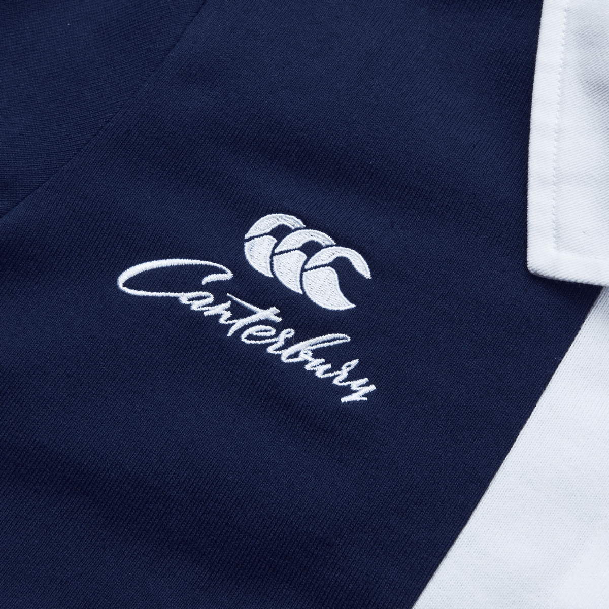 Close-up of the Women's Canterbury Harlequin Weber Long Sleeve Rugby Jersey, showcasing a navy and white design with the iconic brand name and logo embroidered in white on the front.