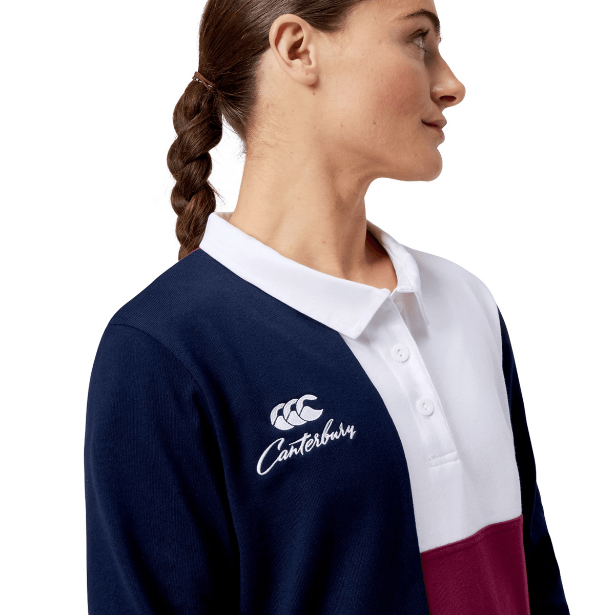 A woman in a Canterbury Women's Harlequin Weber Long Sleeve Rugby Jersey with its distinctive navy, white, and burgundy design looks to the side.