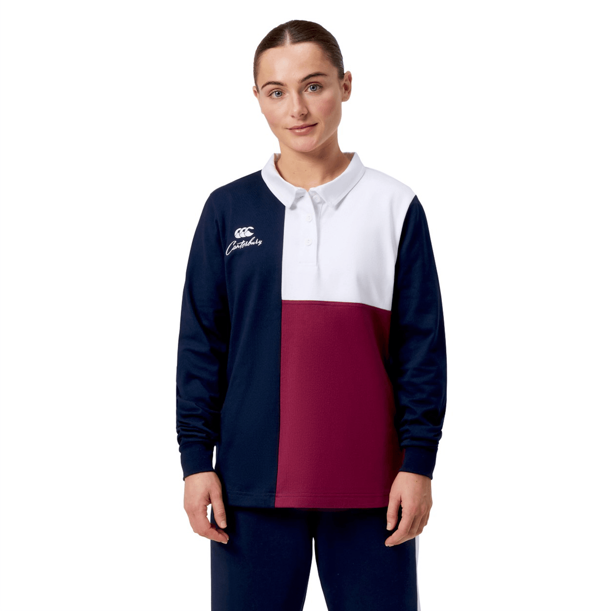 A person models the Women's Canterbury Harlequin Weber Long Sleeve Rugby Jersey in navy, burgundy, and white against a white backdrop, highlighting its subtle Canterbury logo.