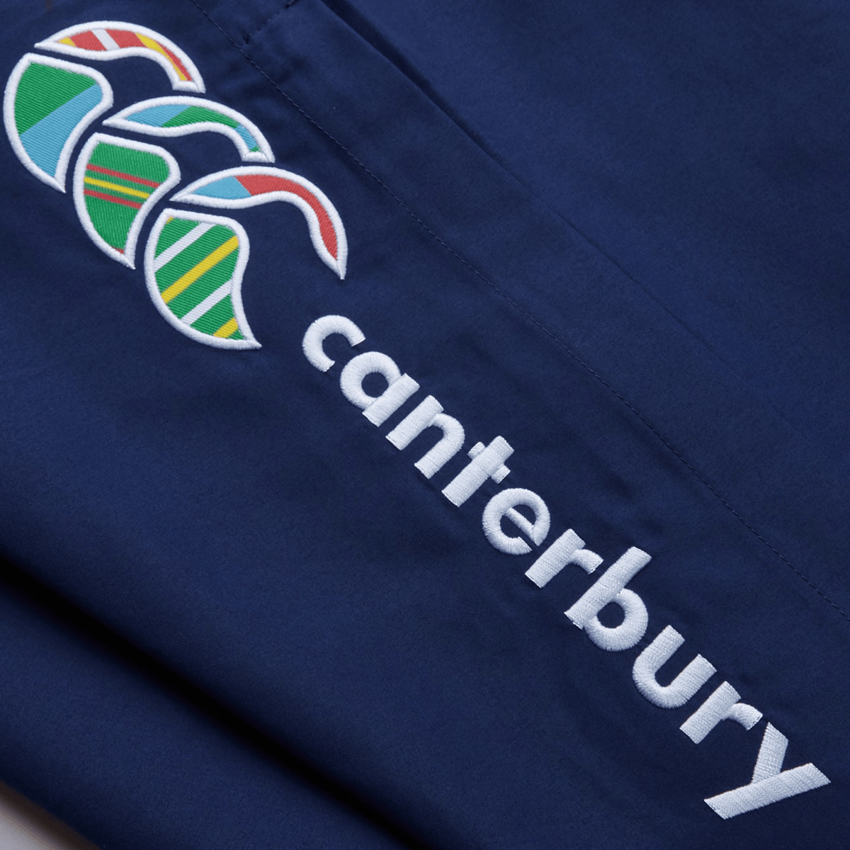 Close-up of navy fabric showcasing the Canterbury Uglies Cuffed Stadium Pant with colorful patterns and white text, highlighting a distinct Rugby Style.