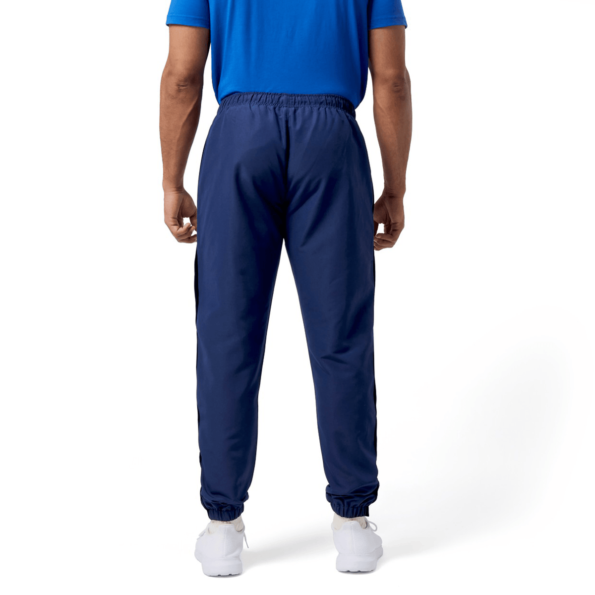 A person is facing away on a plain background, wearing a blue Canterbury Uglies shirt, navy Canterbury Uglies Cuffed Stadium Pant, and white sneakers.