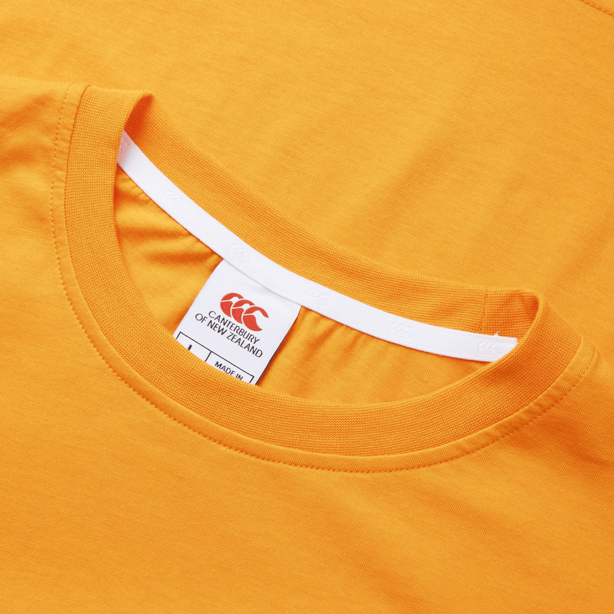 Close-up of an orange Canterbury Fundamental T-Shirt, neatly folded, with the Canterbury CCC logo on the visible clothing tag.