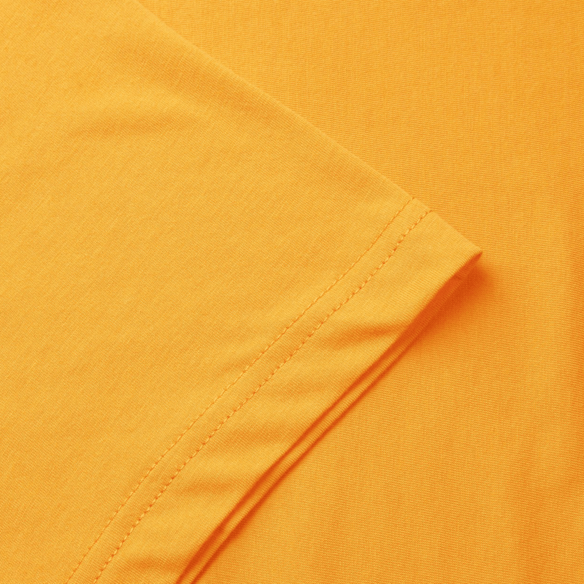 Close-up of Canterbury Fundamental T-Shirt's orange fabric, showcasing a folded sleeve with visible stitching, complemented by its classic fit and iconic CCC logo.
