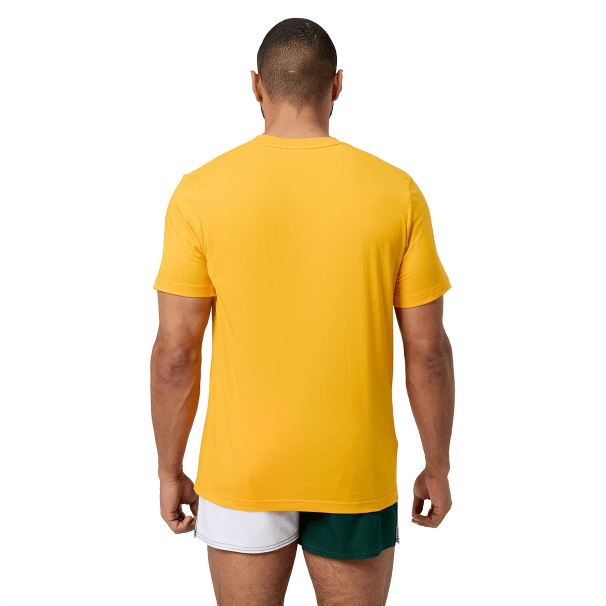 A person is seen from the rear, wearing a Canterbury Fundamental T-Shirt paired with yellow and green shorts, prominently displaying the CCC logo against a clean white background.