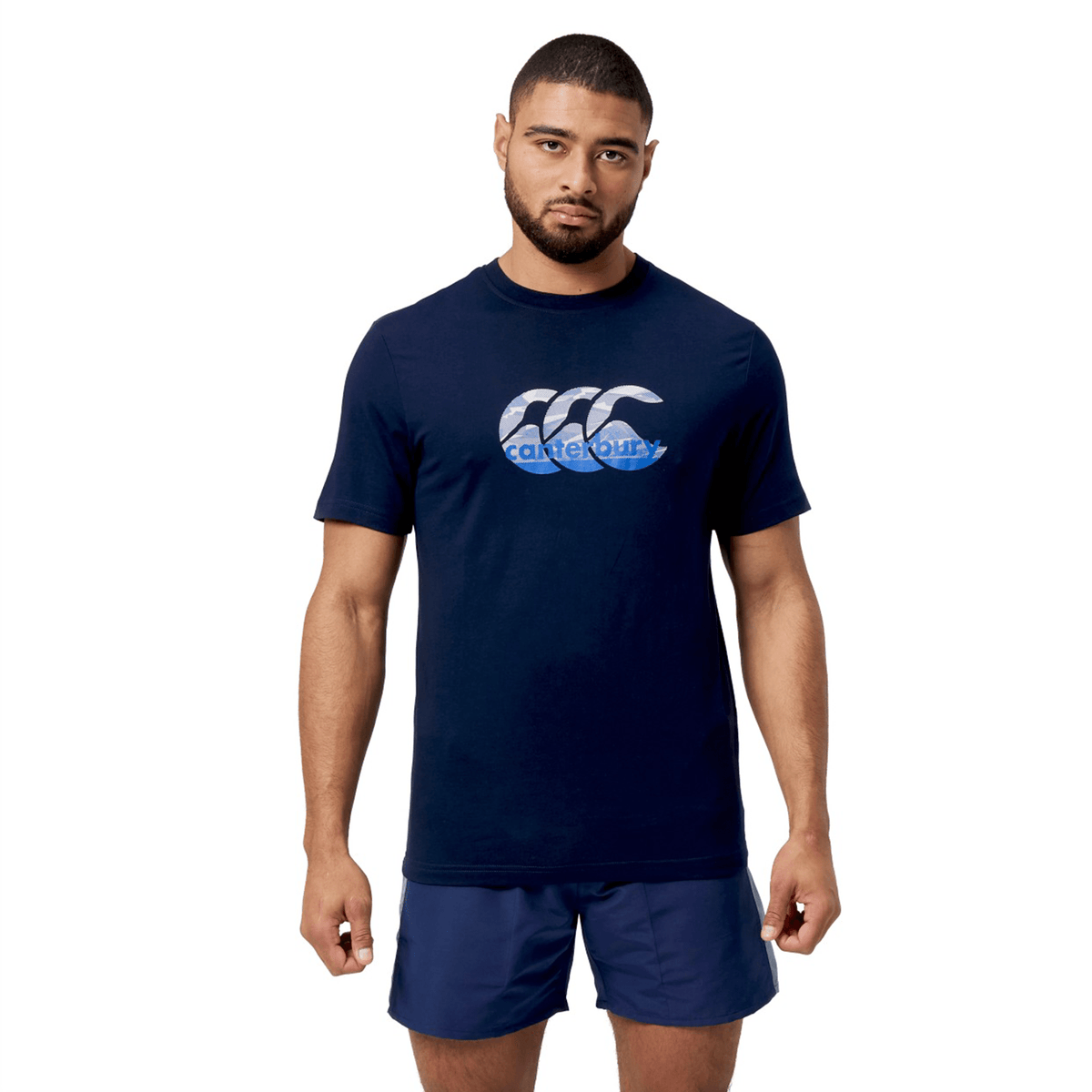 A man models a navy Canterbury Fundamental T-Shirt featuring the iconic CCC logo, paired with matching shorts against a white background.