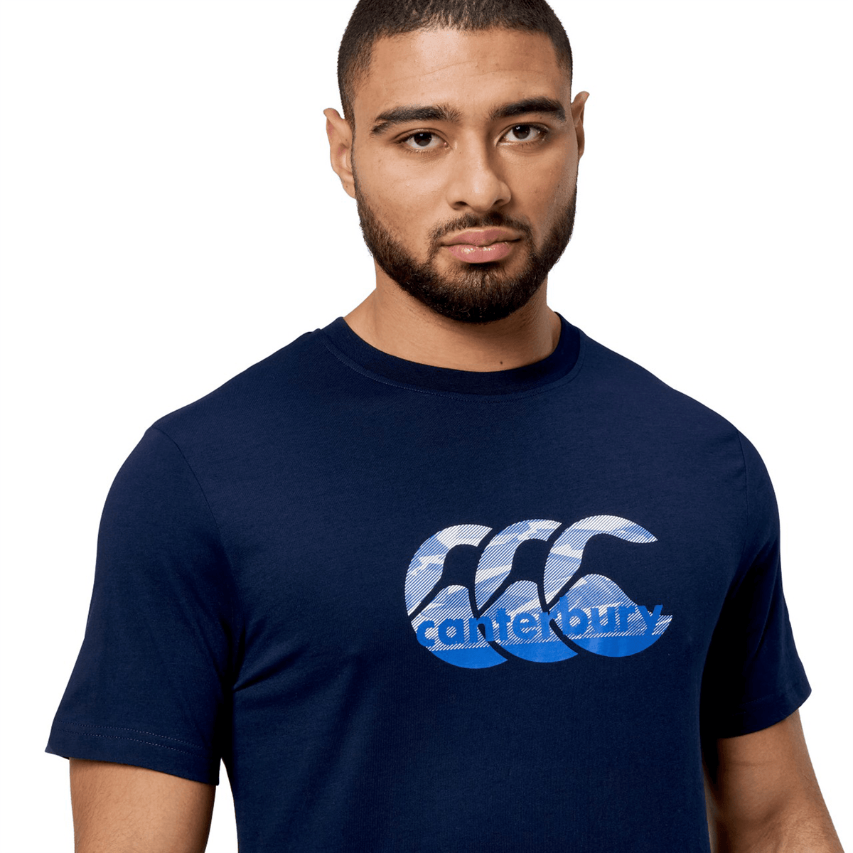 A person wears a classic fit Canterbury Fundamental T-Shirt with a stylized CCC logo, navy blue in color, against a plain white background.
