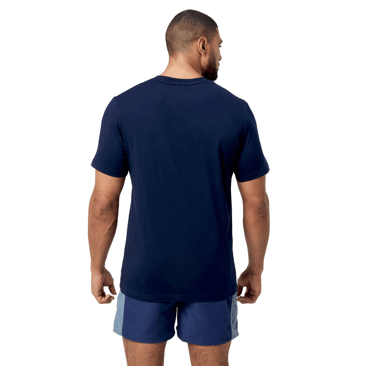 Against a white backdrop, a man in a Canterbury Fundamental T-Shirt by Canterbury stands with his back to the camera, highlighting the CCC logo design and classic fit.