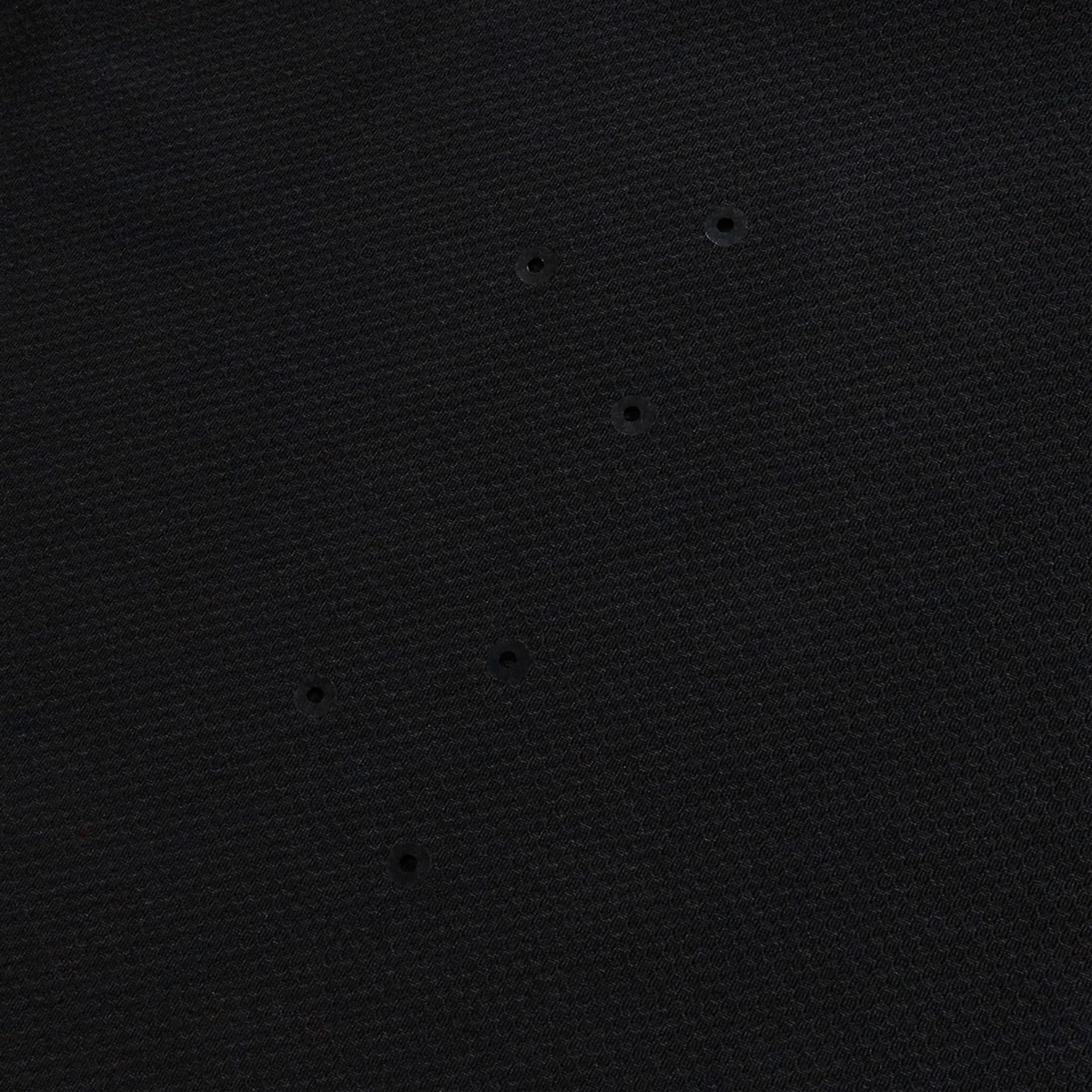 The Everest Training Tee by Canterbury features black textured fabric with six small, evenly spaced holes for breathability—a performance fit designed especially for rugby players.